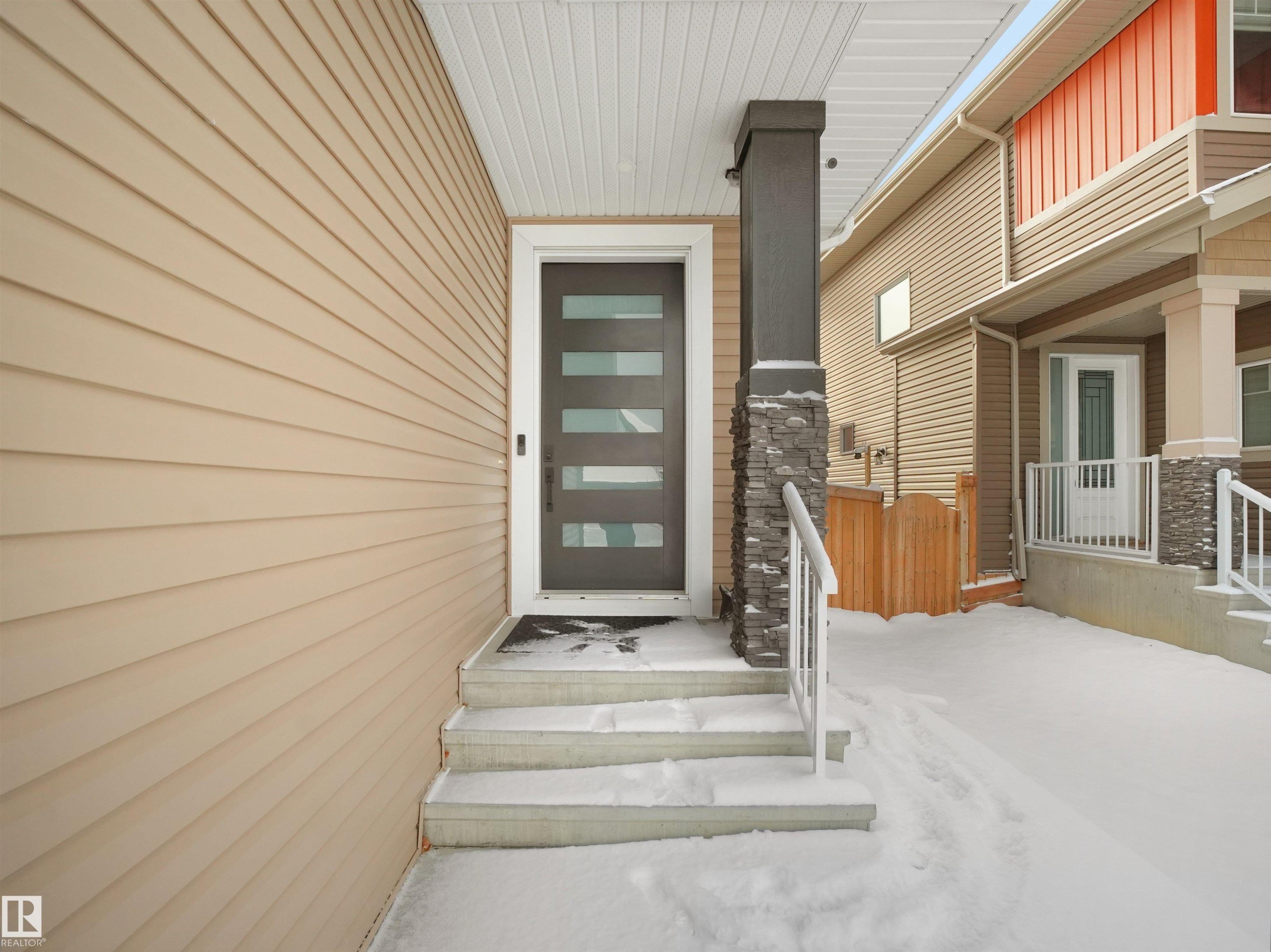 Modern entry door with horizontal glass inserts, flanked by light beige horizontal siding - 20827 130 Avenue Nw, Edmonton, AB - Outdoor With Deck Patio Veranda