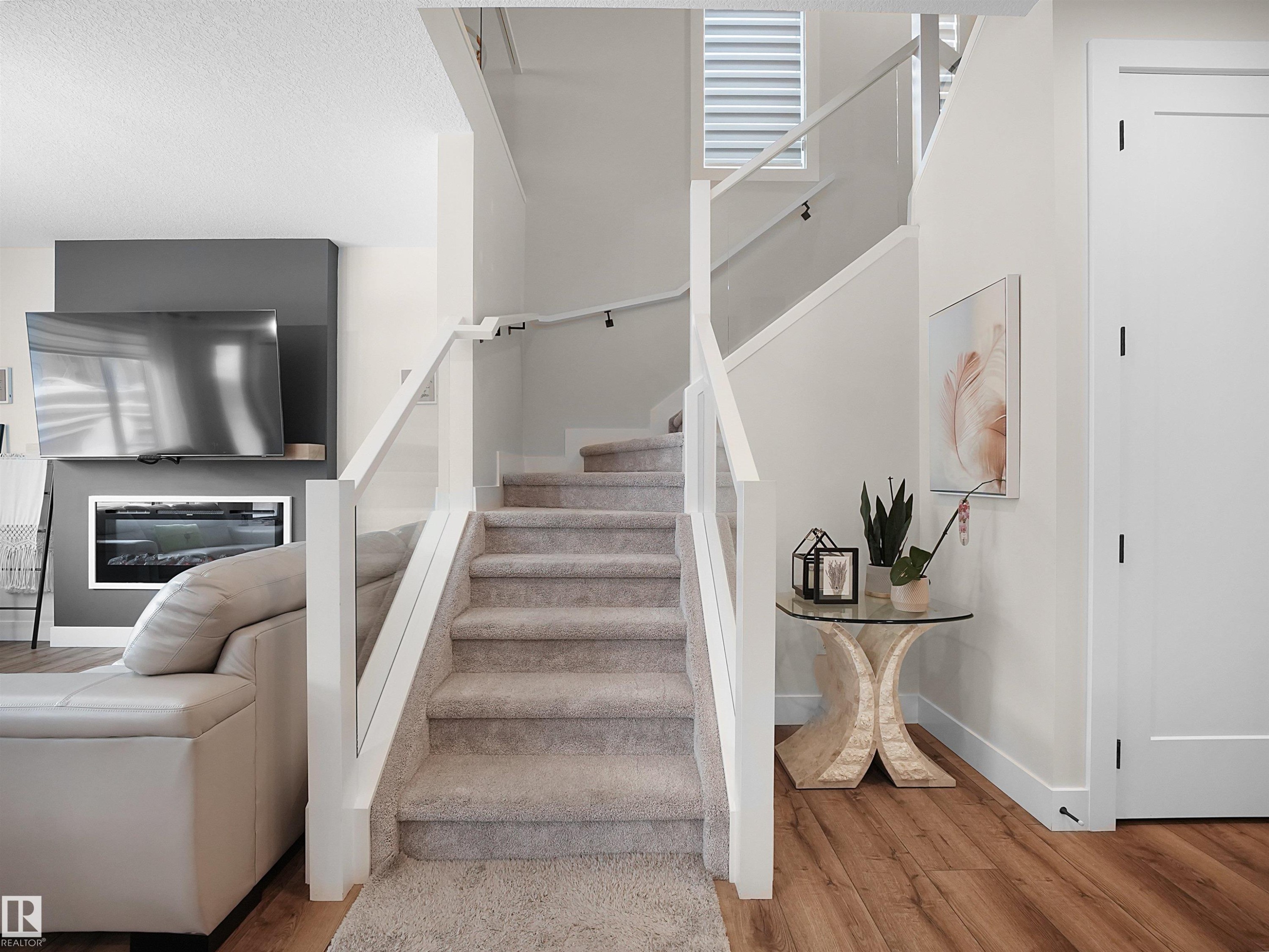 Carpeted staircase with contemporary glass panel railing - 20827 130 Avenue Nw, Edmonton, AB - Indoor Photo Showing Other Room With Fireplace