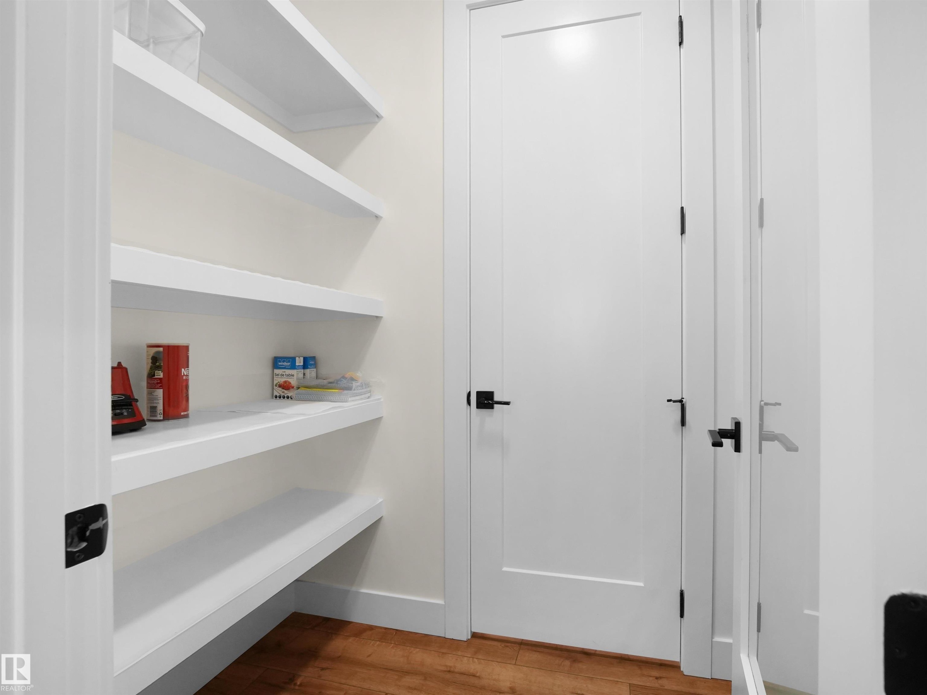 Built-in pantry shelving featuring five levels of storage, white trim, and wood-finish flooring - 20827 130 Avenue Nw, Edmonton, AB - Indoor