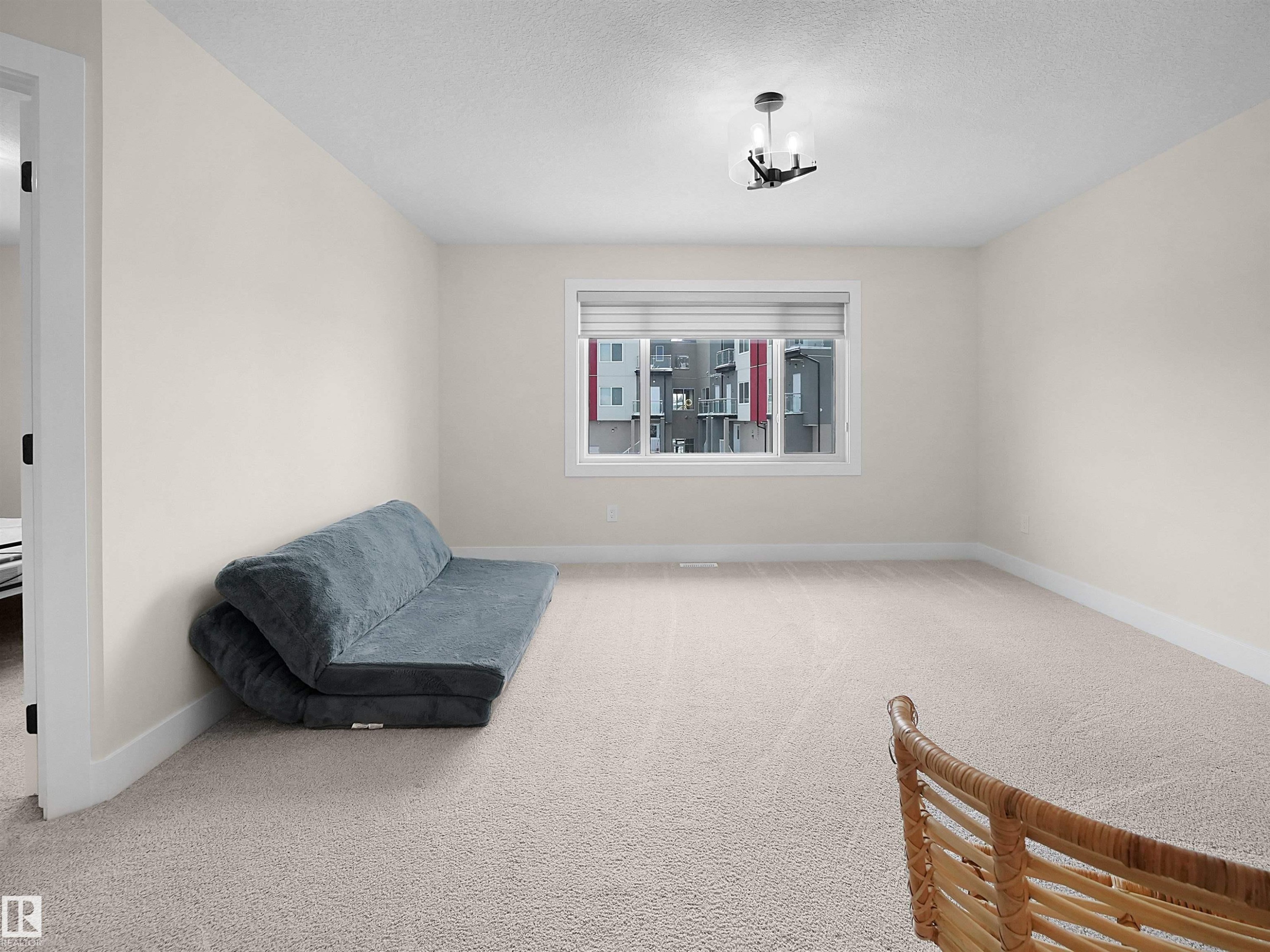 Spacious room featuring neutral carpeting, a large window with blinds, and a contemporary ceiling light fixture - 20827 130 Avenue Nw, Edmonton, AB - Indoor