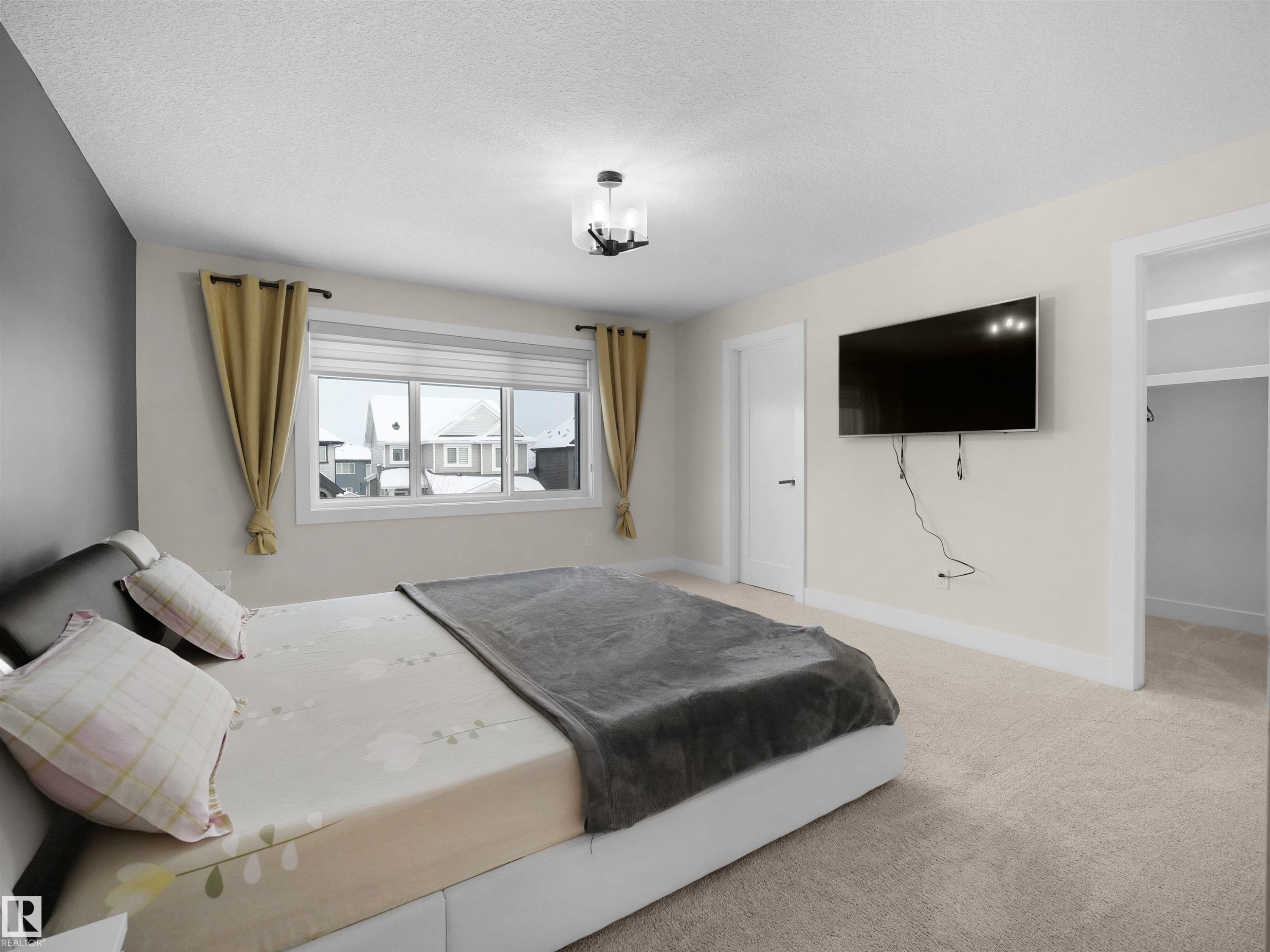 Spacious room featuring neutral carpeting, a large window, a ceiling-mounted light fixture, and a doorway opening to an additional area - 20827 130 Avenue Nw, Edmonton, AB - Indoor Photo Showing Bedroom