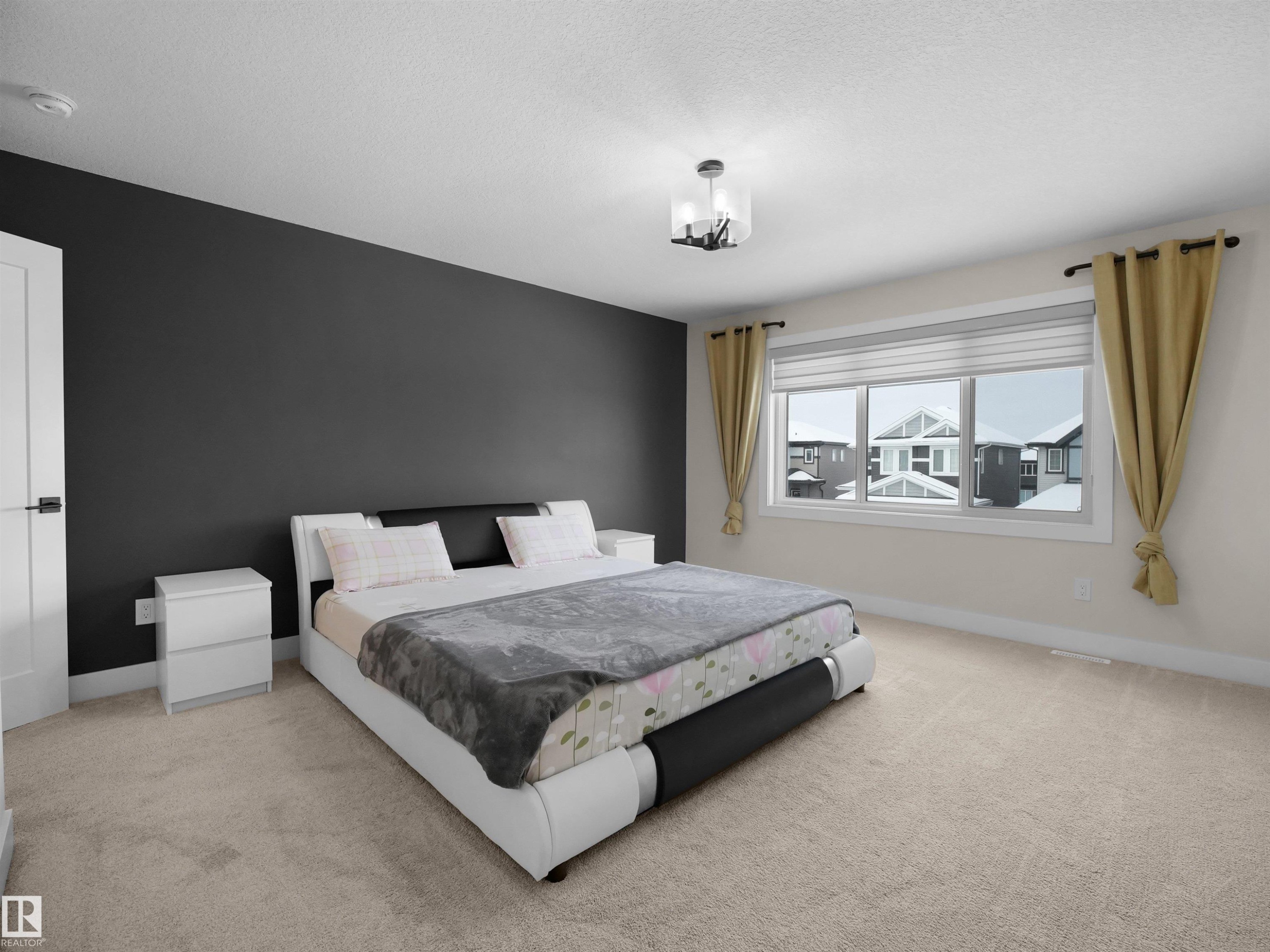 Spacious room featuring a large window, neutral carpeting, a dark accent wall, a solid white door, and a contemporary ceiling fixture - 20827 130 Avenue Nw, Edmonton, AB - Indoor Photo Showing Bedroom