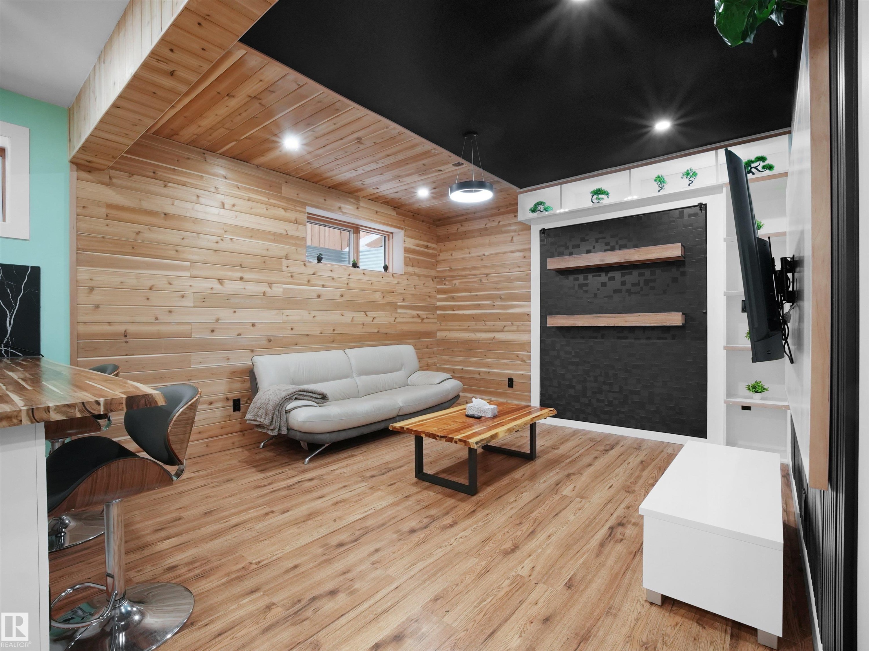 Entertainment space featuring wood-finish flooring, accent wall paneling, built-in shelving, recessed lighting, and a black ceiling - 20827 130 Avenue Nw, Edmonton, AB - Indoor Photo Showing Other Room