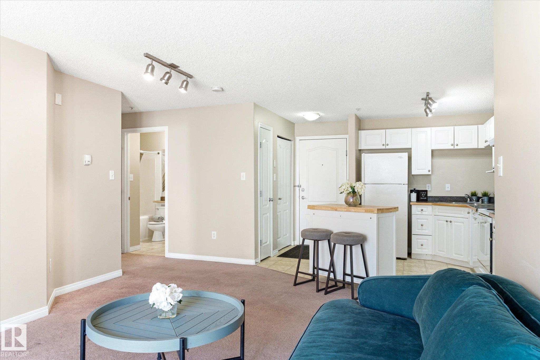 Open-concept living space featuring neutral wall tones and coordinating carpeting - 203 155 Edwards Drive, Edmonton, AB - Indoor Photo Showing Other Room