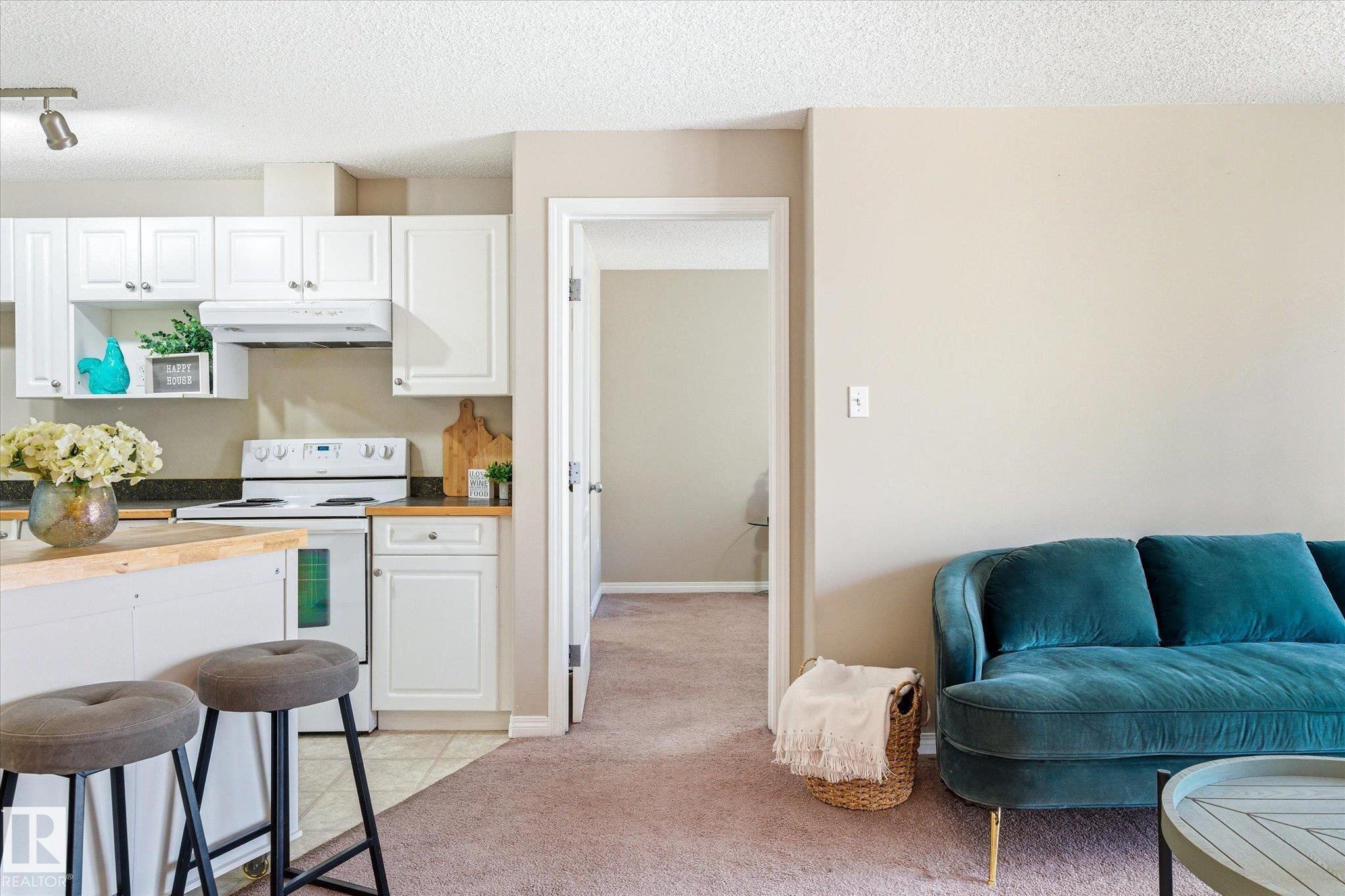 Open-concept kitchen featuring white cabinetry, light-colored countertops, and white appliances - 203 155 Edwards Drive, Edmonton, AB - Indoor