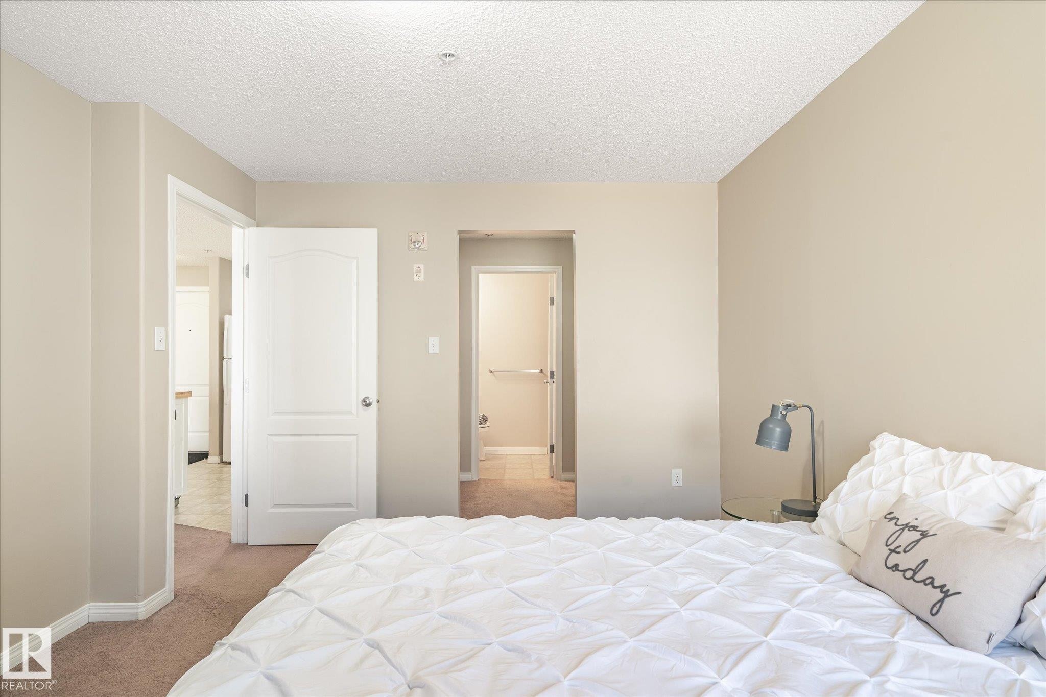 Neutral-toned bedroom featuring wall-to-wall carpeting and textured ceilings - 203 155 Edwards Drive, Edmonton, AB - Indoor Photo Showing Bedroom