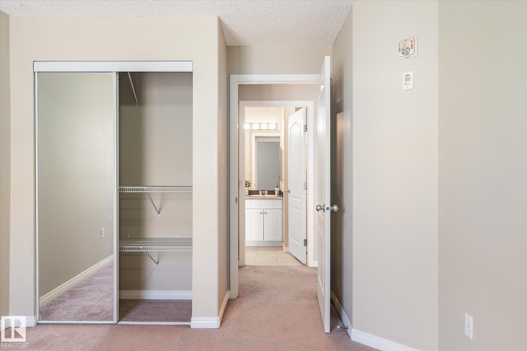 Mirrored closet doors featuring wire shelving - 203 155 Edwards Drive, Edmonton, AB - Indoor Photo Showing Other Room