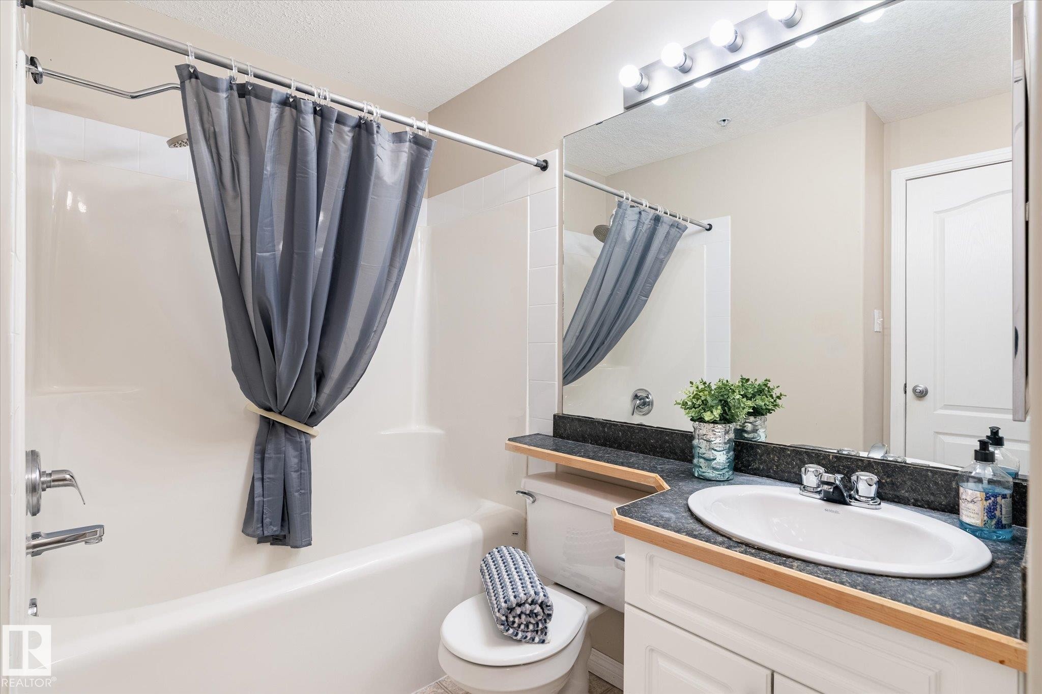 Full bathroom featuring a white porcelain tub and shower combination with chrome fixtures - 203 155 Edwards Drive, Edmonton, AB - Indoor Photo Showing Bathroom