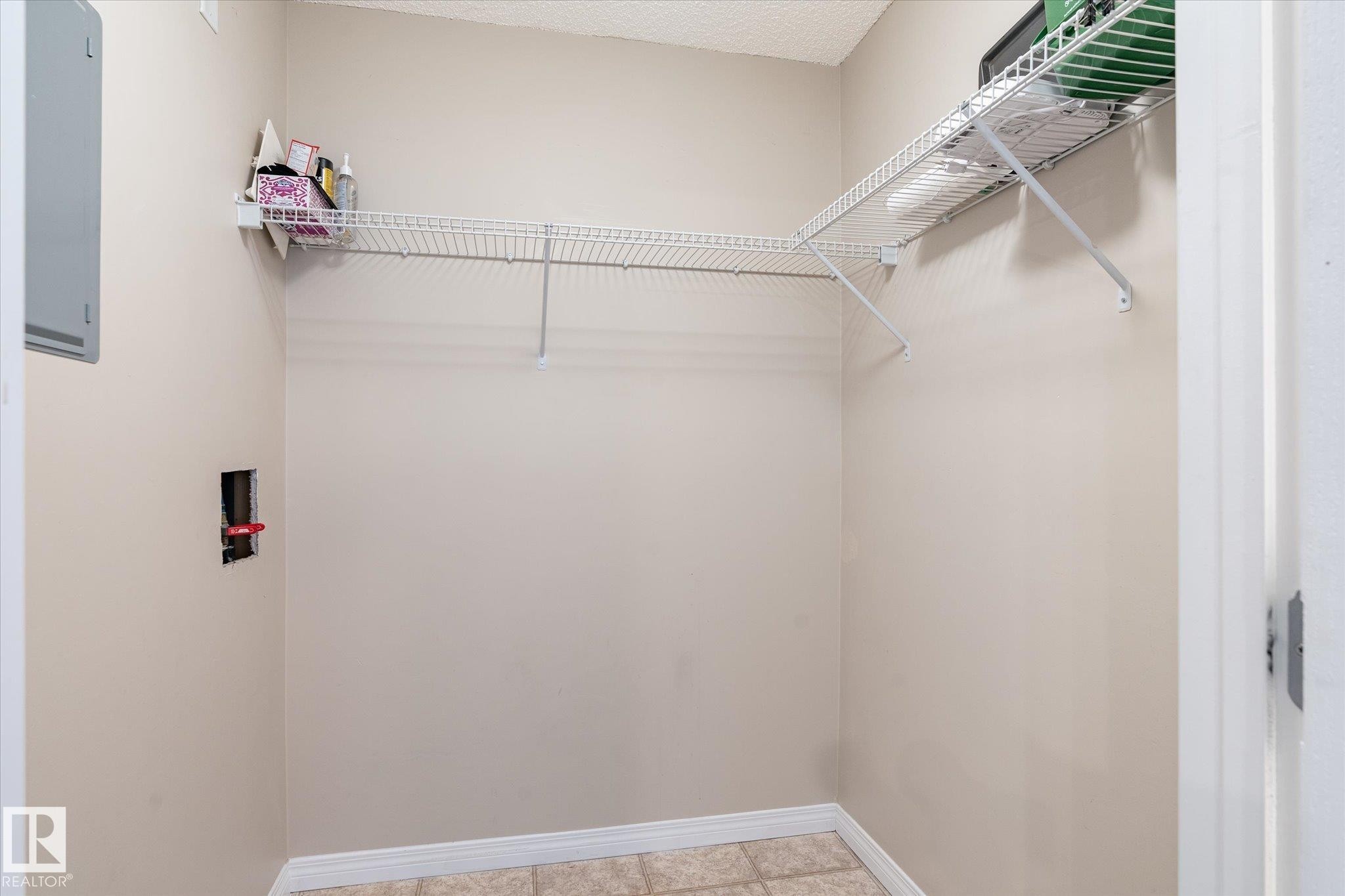 Laundry area with neutral wall paint, wire shelving, and tile flooring - 203 155 Edwards Drive, Edmonton, AB - Indoor With Storage