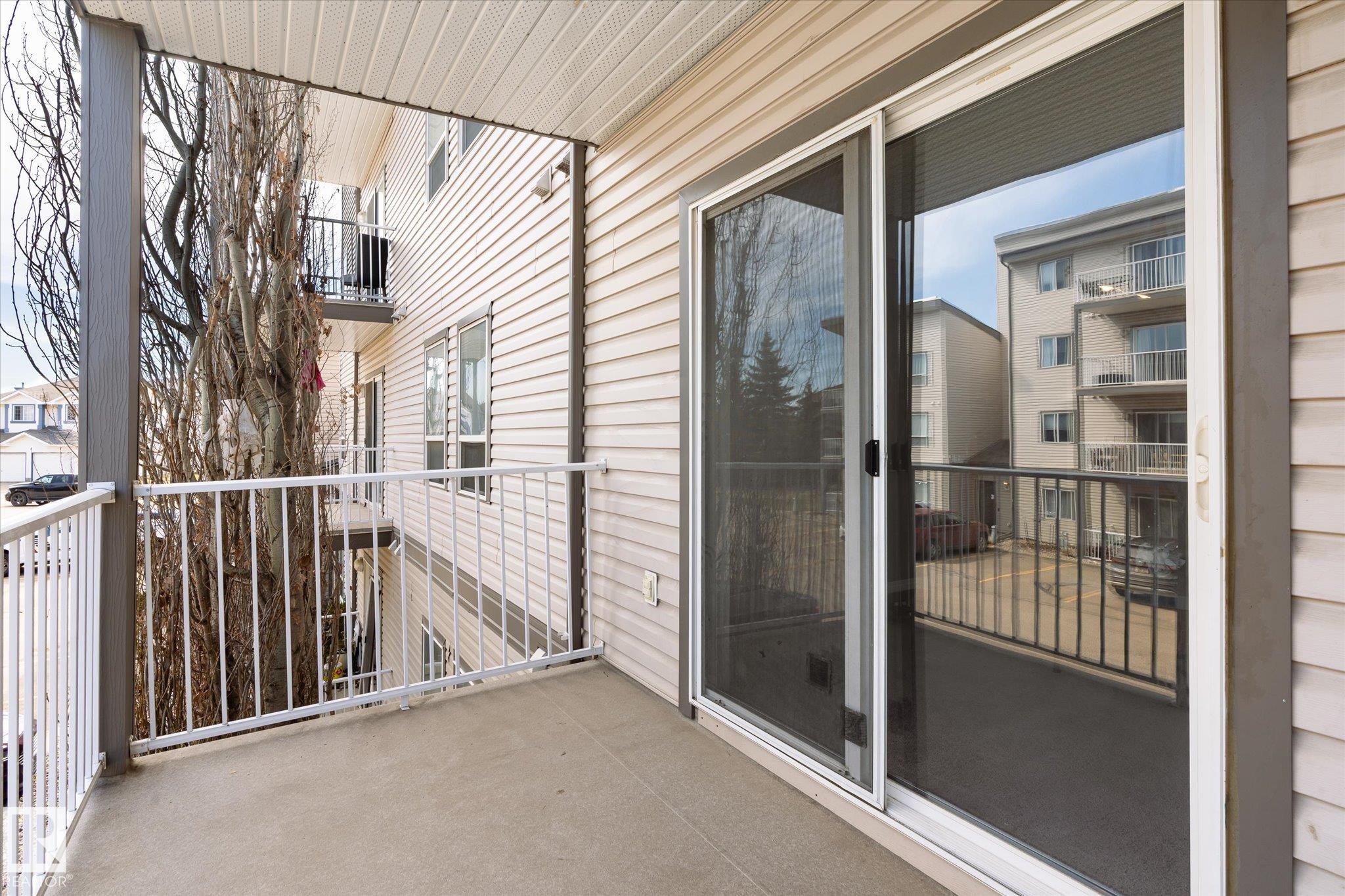 Private balcony with concrete flooring, white metal railing, and vinyl siding - 203 155 Edwards Drive, Edmonton, AB - Outdoor With Balcony With Exterior