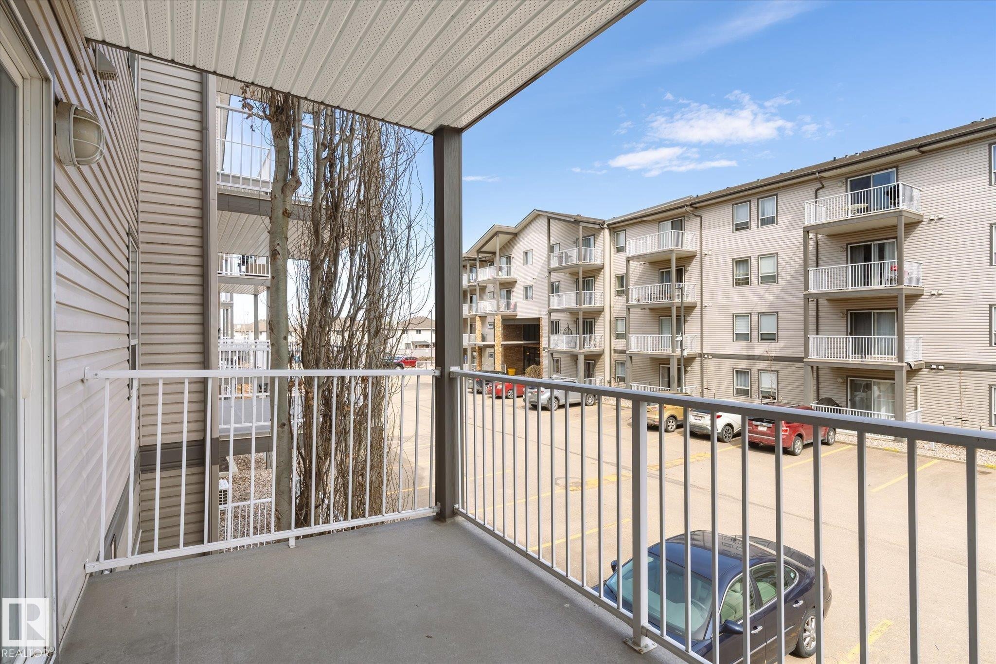 Private balcony with light gray concrete flooring and white metal railing - 203 155 Edwards Drive, Edmonton, AB - Outdoor With Balcony With Exterior