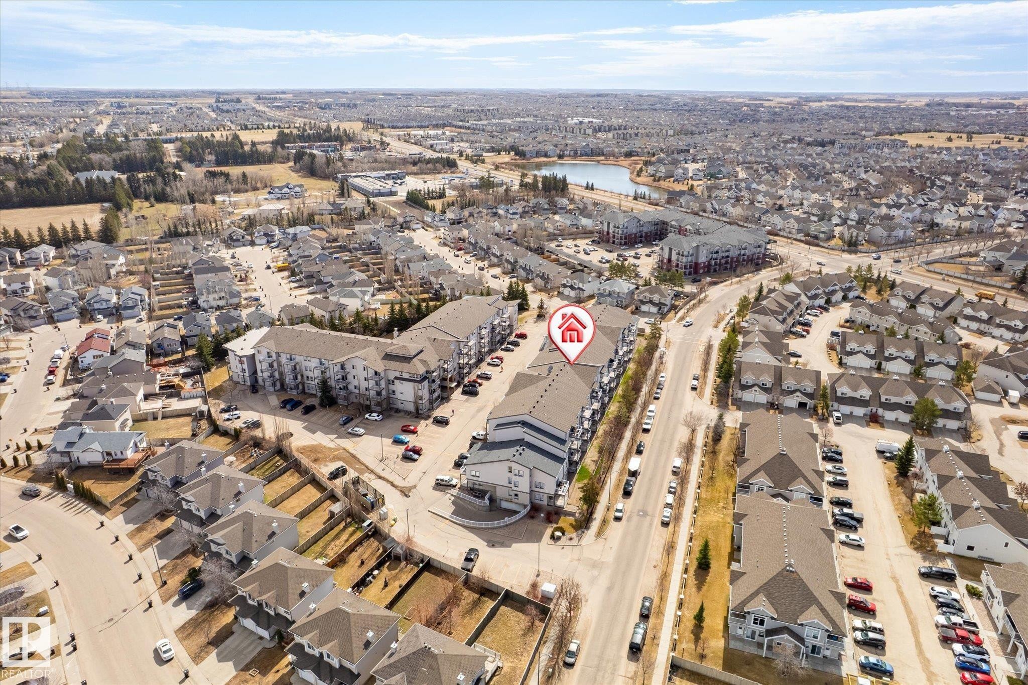 Aerial perspective showcasing a multi-story residential building with grey roofing and light-colored facades - 203 155 Edwards Drive, Edmonton, AB - Outdoor With View