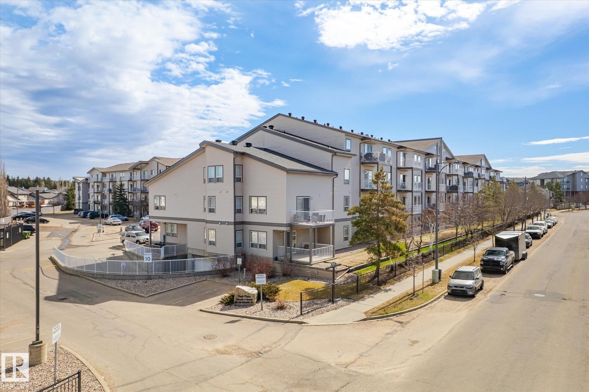 Multi-level apartment building featuring a light-colored exterior and dark-toned roofing - 203 155 Edwards Drive, Edmonton, AB - Outdoor With Balcony