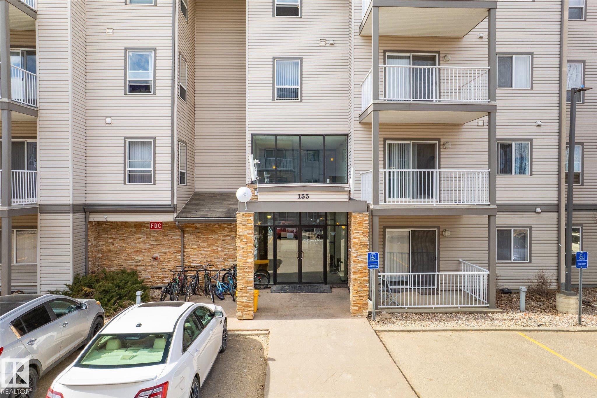 Multi-story building featuring light-colored horizontal siding and stone veneer accents - 203 155 Edwards Drive, Edmonton, AB - Outdoor With Balcony With Facade