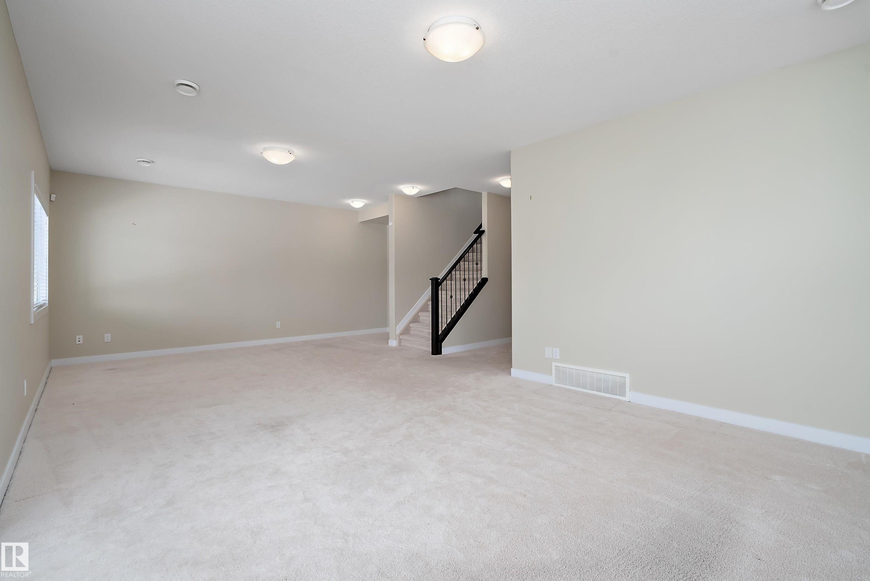Spacious room featuring neutral carpeting and light-toned walls - 14 3090 Cameron Heights Way, Edmonton, AB - Indoor Photo Showing Other Room
