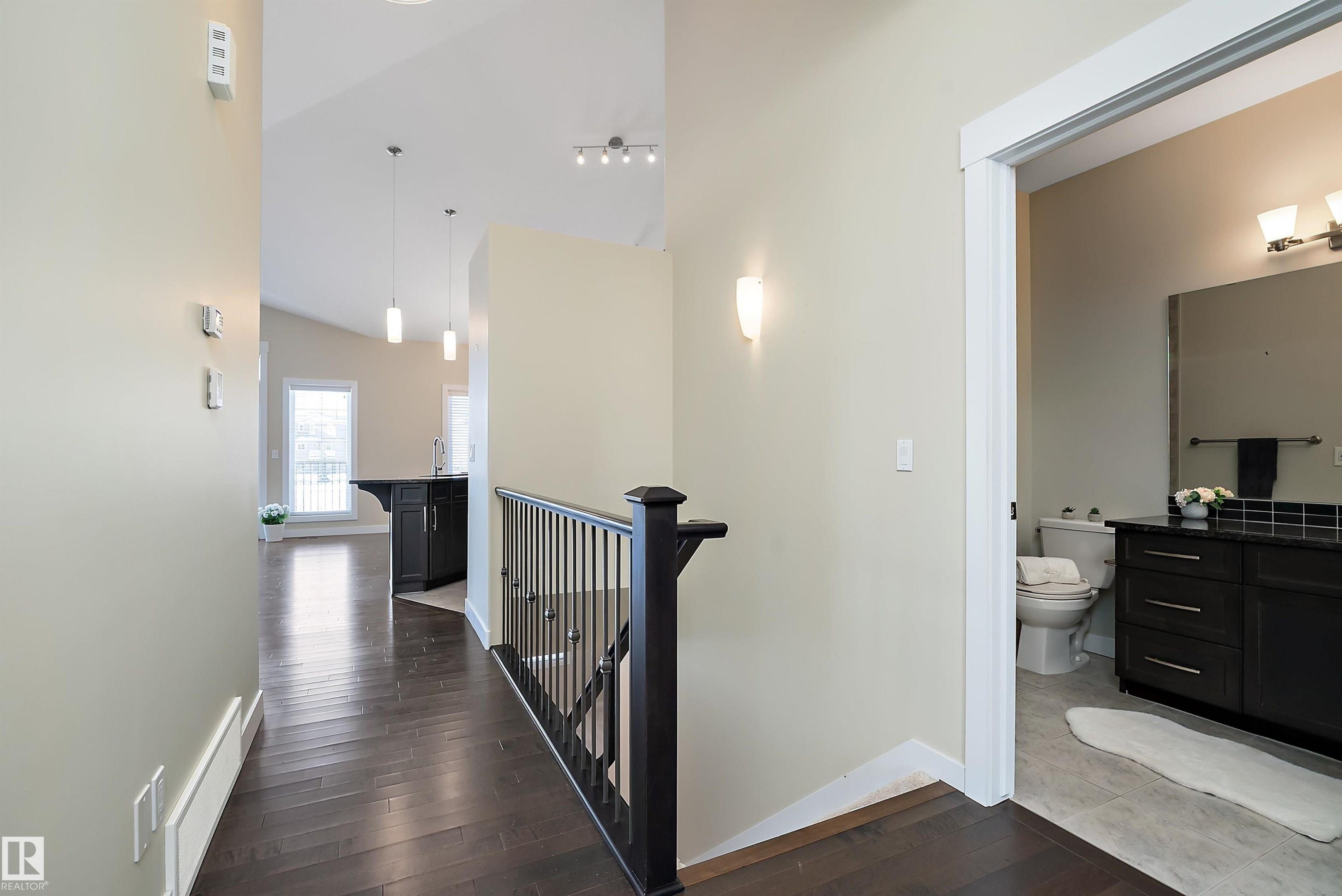 Hallway featuring dark wood-finish flooring, a contemporary staircase railing, and a vaulted ceiling - 14 3090 Cameron Heights Way, Edmonton, AB - Indoor Photo Showing Other Room