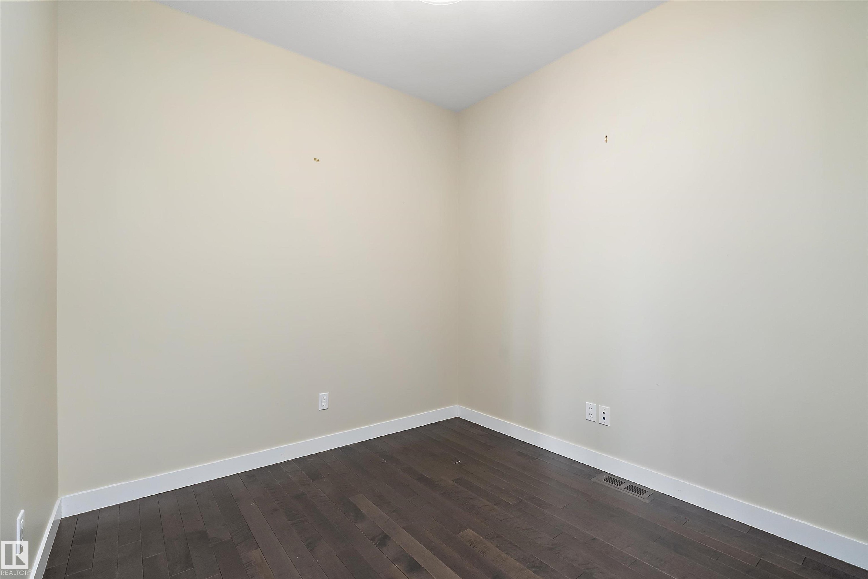 Room with light neutral wall paint, dark wood-finish flooring, and white baseboards - 14 3090 Cameron Heights Way, Edmonton, AB - Indoor Photo Showing Other Room