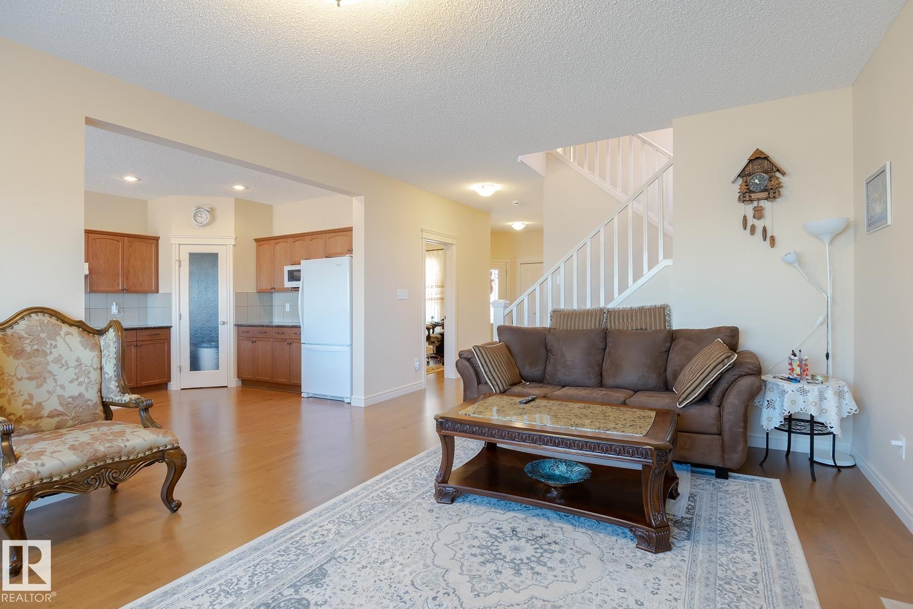 Open-concept living space with wood-finish flooring, a white spindle staircase, and recessed lighting - 7426 Getty Way, Edmonton, AB - Indoor Photo Showing Living Room