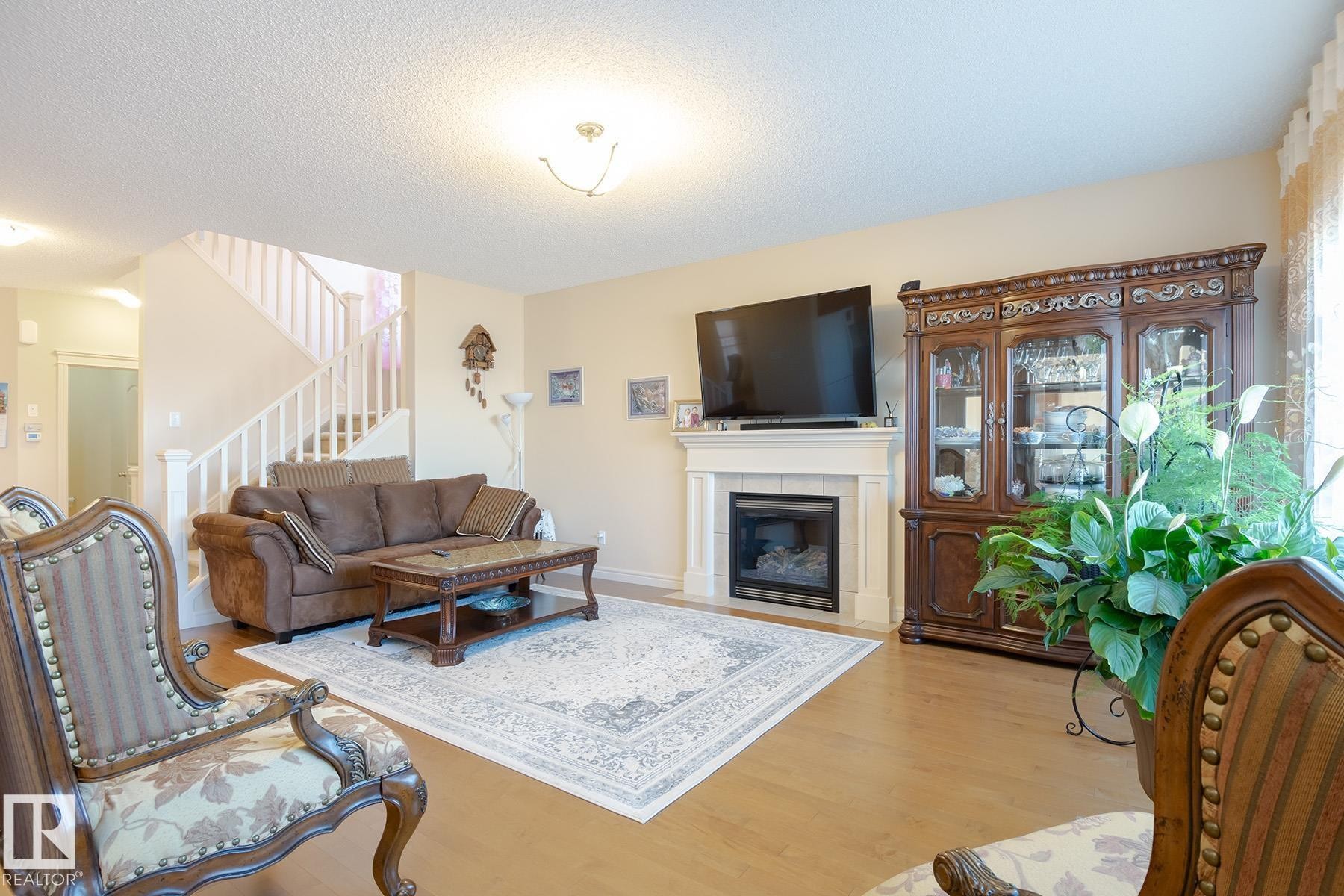 Living area featuring wood-finish flooring, a white mantel, and an integrated fireplace - 7426 Getty Way, Edmonton, AB - Indoor Photo Showing Living Room With Fireplace