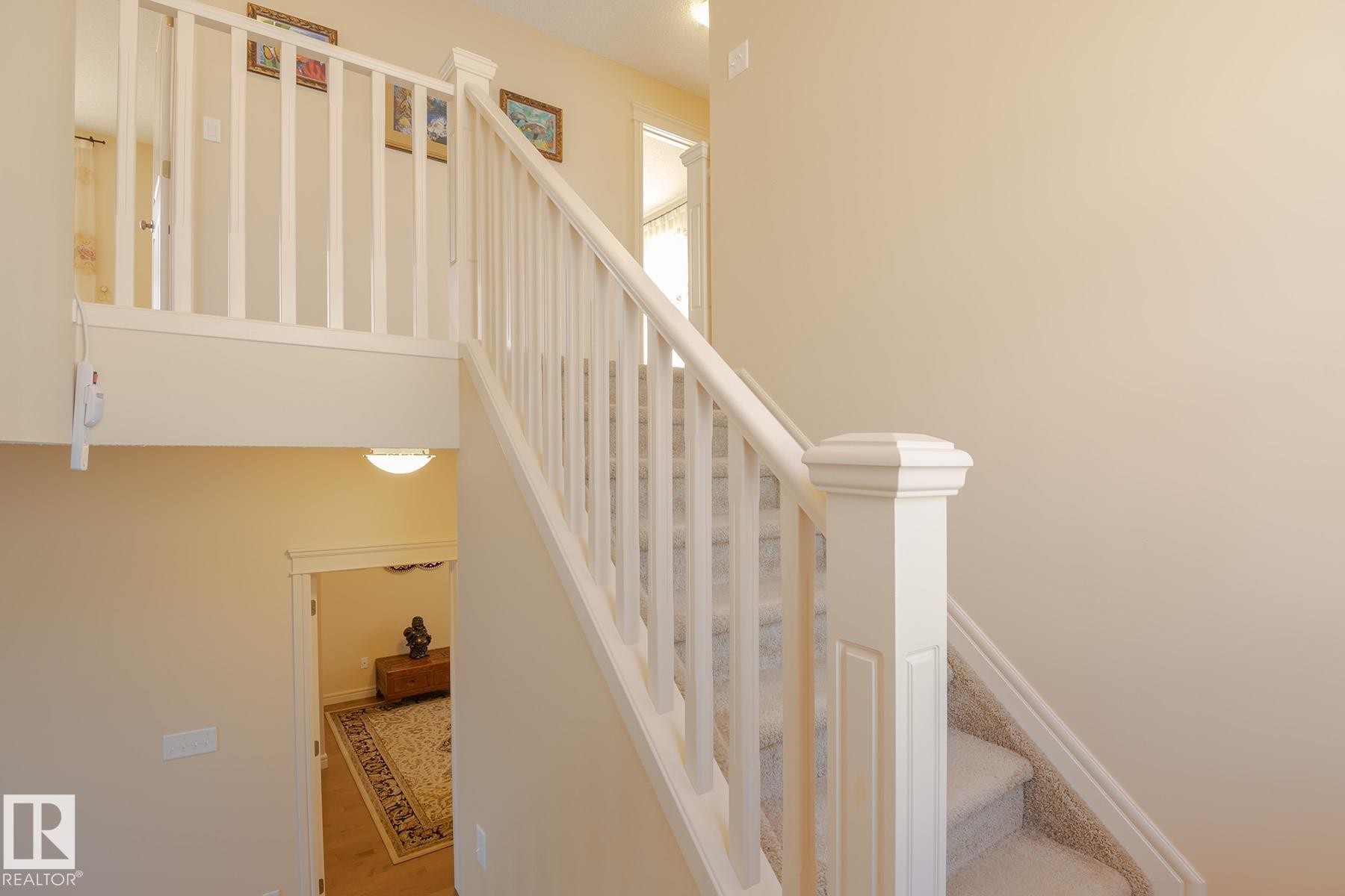 Staircase featuring white balusters and newel post, carpeted treads, and a neutral wall color - 7426 Getty Way, Edmonton, AB - Indoor Photo Showing Other Room