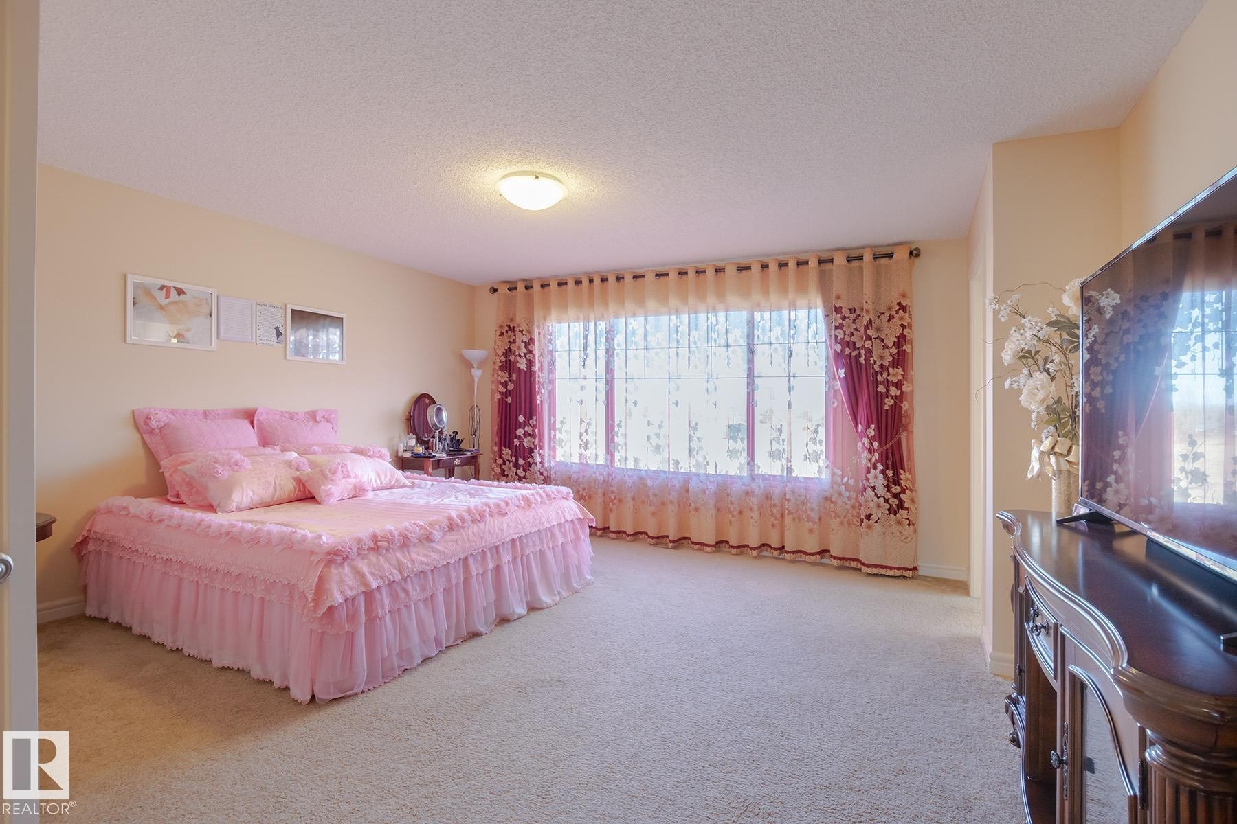 Spacious room with large windows, wall-to-wall carpeting, a built-in overhead light fixture, and light-colored walls - 7426 Getty Way, Edmonton, AB - Indoor Photo Showing Bedroom