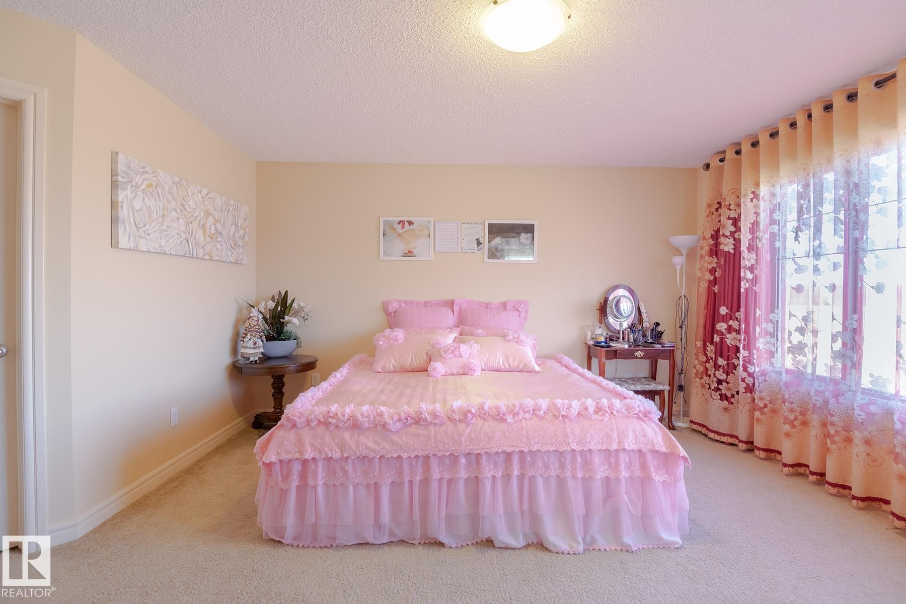 Carpeted room featuring a ceiling-mounted light fixture, neutral wall color, and a window with patterned curtains - 7426 Getty Way, Edmonton, AB - Indoor Photo Showing Bedroom