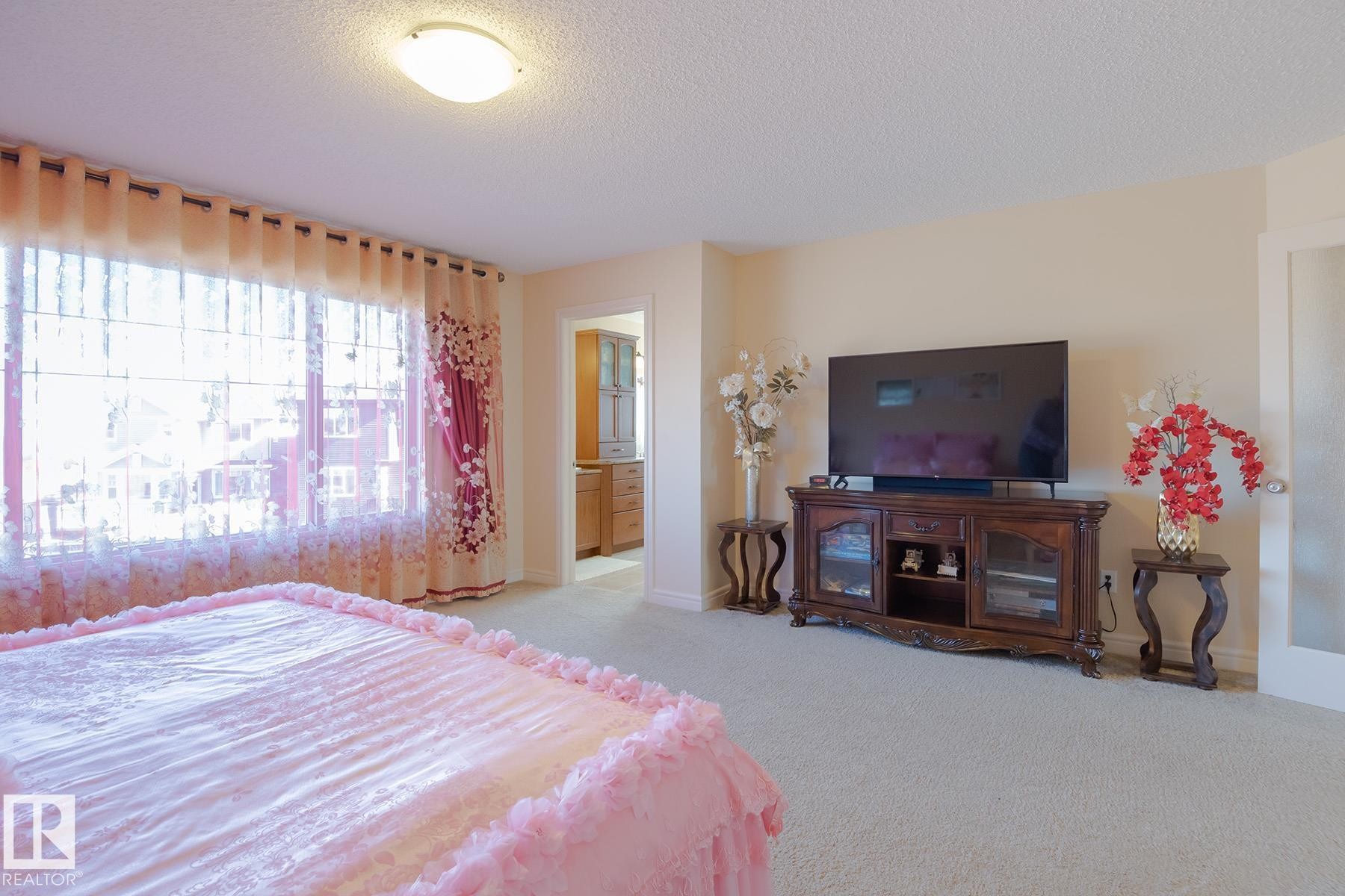 Carpeted room with a wide window, ceiling light fixture, and an open doorway revealing cabinetry - 7426 Getty Way, Edmonton, AB - Indoor Photo Showing Bedroom