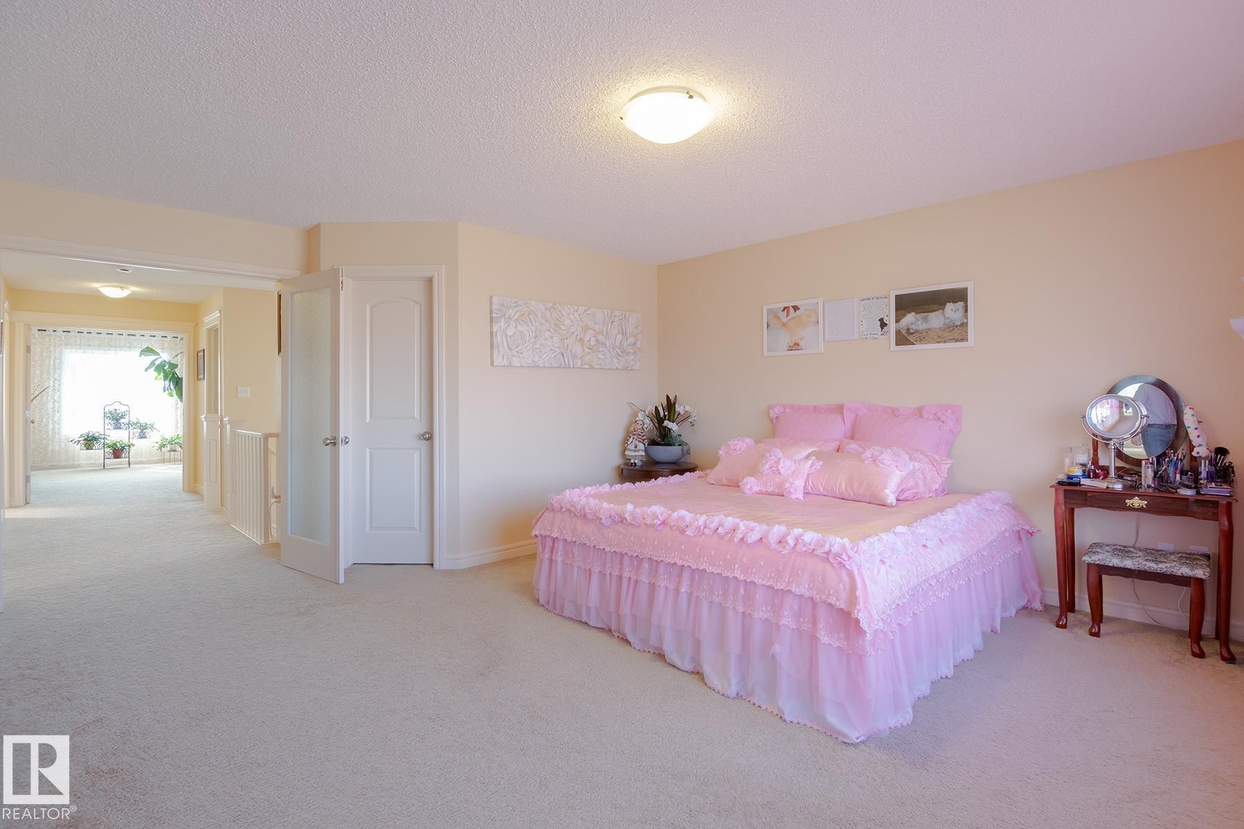 Carpeted room with a hallway entry, featuring a tray ceiling and recessed lighting - 7426 Getty Way, Edmonton, AB - Indoor Photo Showing Bedroom