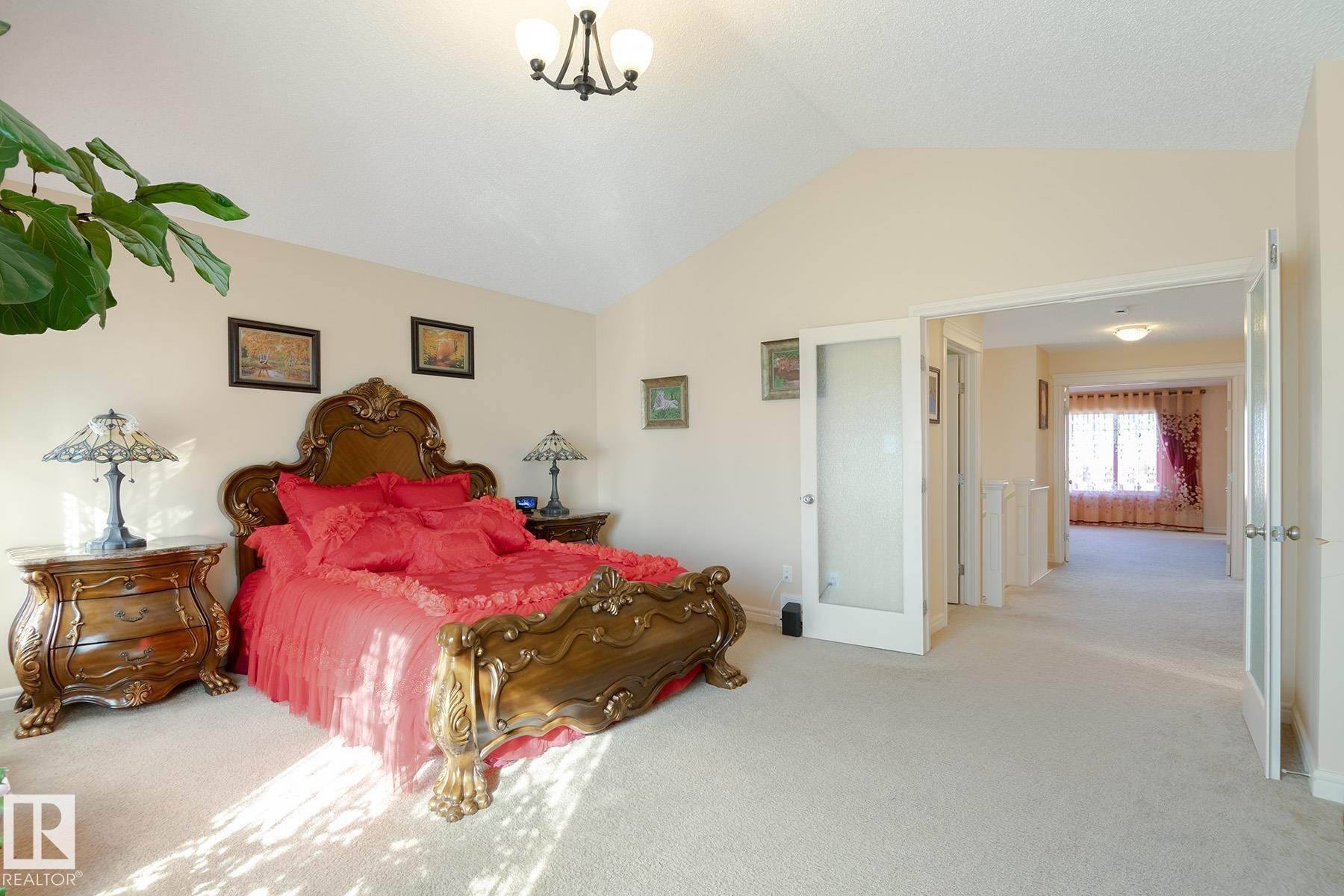 Bedroom featuring vaulted ceilings, plush carpeting, and an open entryway to a hallway with additional rooms - 7426 Getty Way, Edmonton, AB - Indoor Photo Showing Bedroom