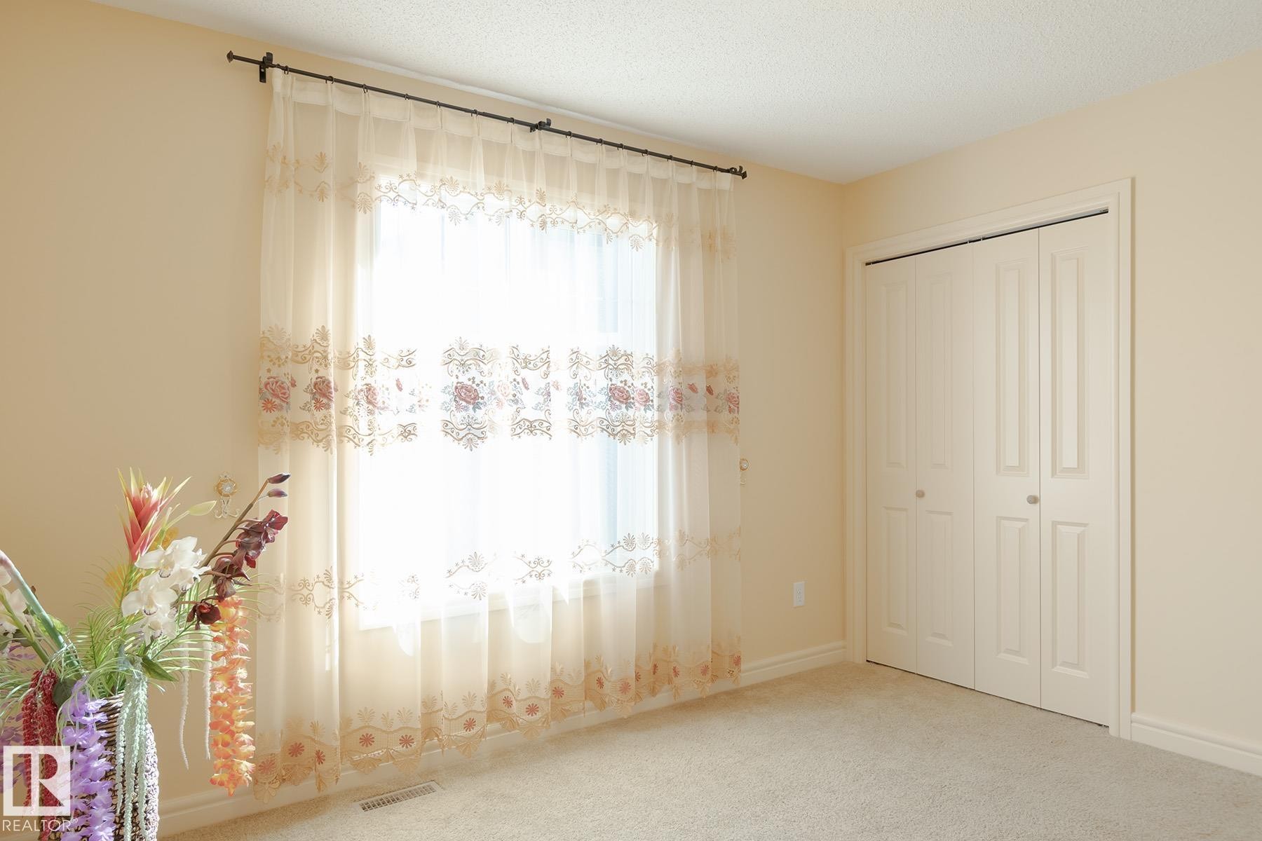 Neutral-toned walls and plush carpeting complement the bi-fold closet doors - 7426 Getty Way, Edmonton, AB - Indoor Photo Showing Other Room
