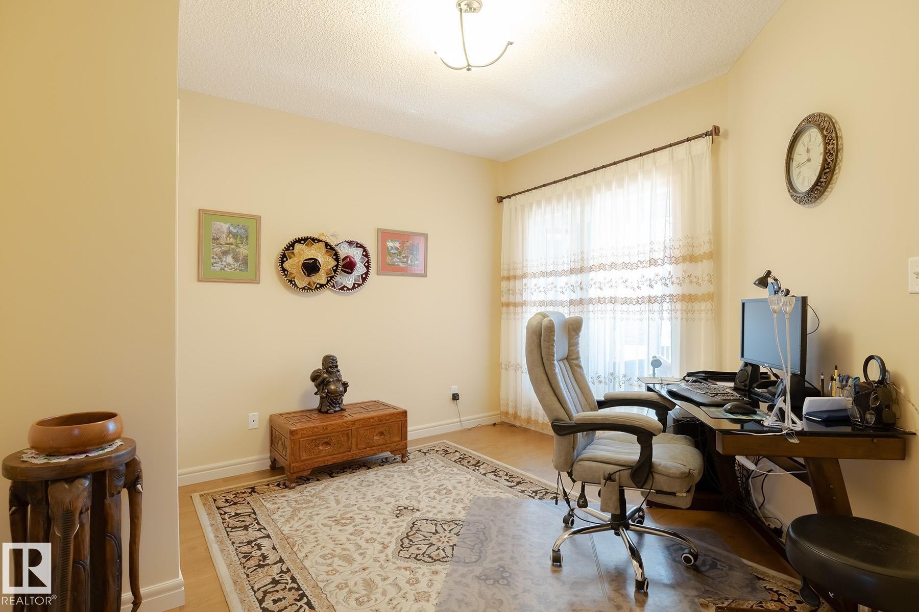 Bright room featuring a large window with sheer curtains, light-toned walls, and wood-finish flooring - 7426 Getty Way, Edmonton, AB - Indoor Photo Showing Office