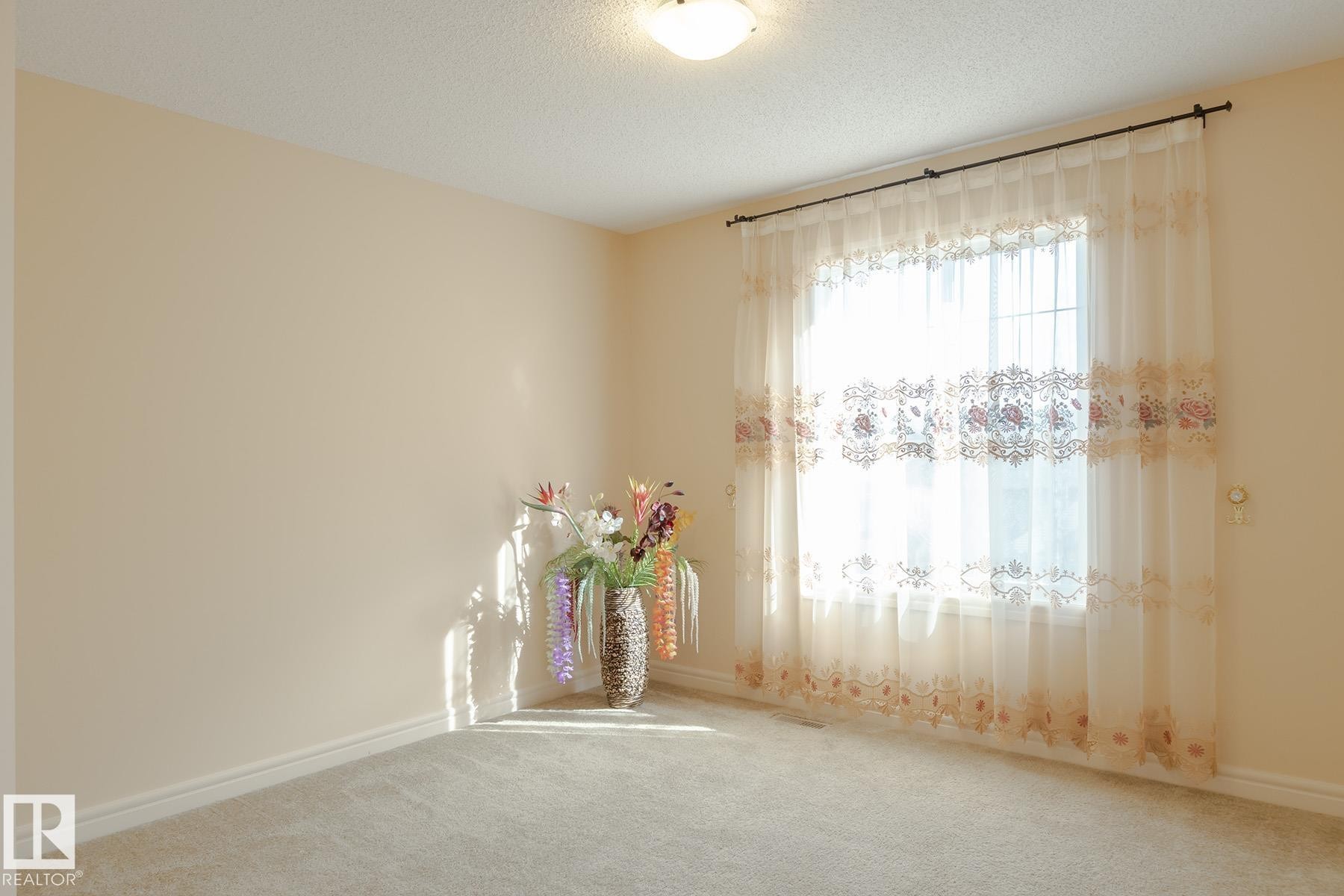 Bright room featuring neutral wall paint, light-colored carpet flooring, a window with sheer curtains, and a ceiling-mounted light fixture - 7426 Getty Way, Edmonton, AB - Indoor Photo Showing Other Room