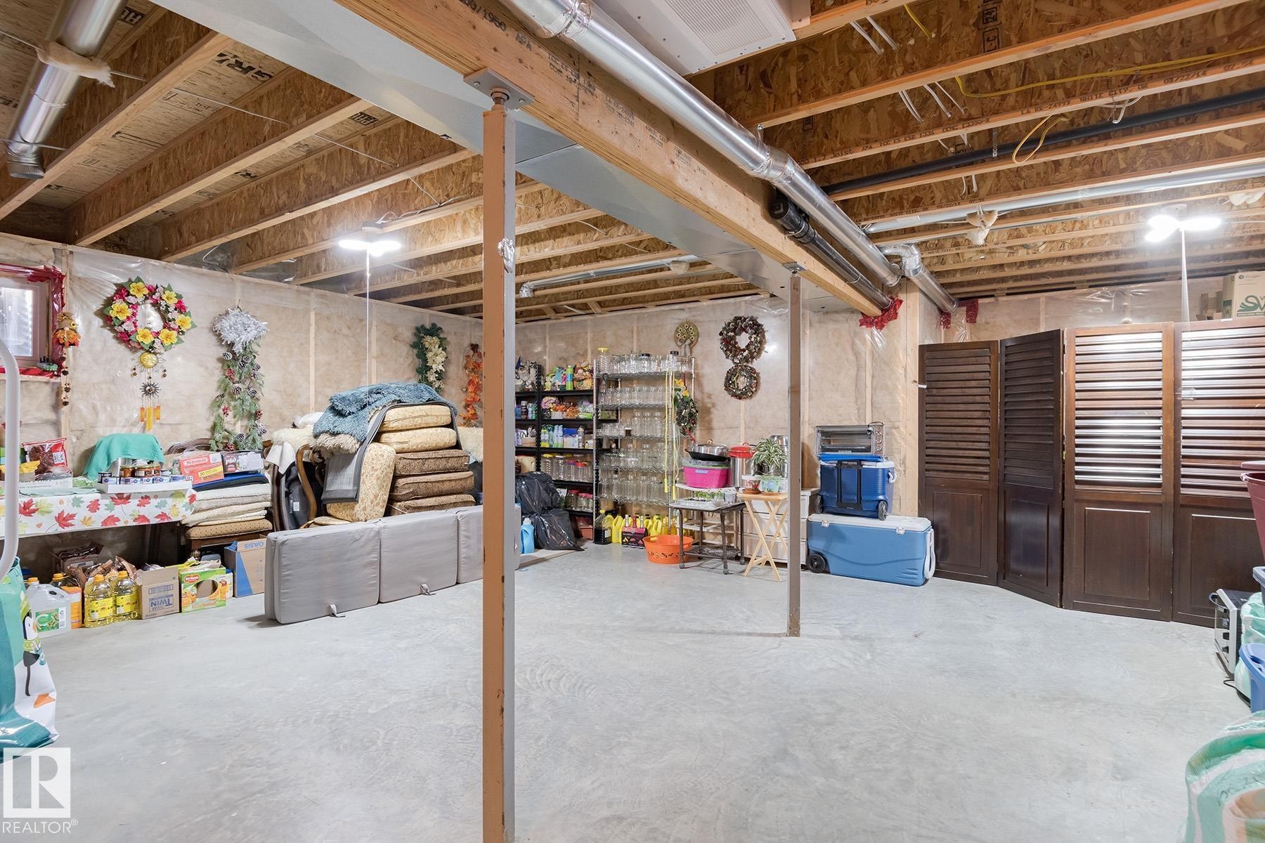 Unfinished basement area with exposed wood joists and concrete flooring, featuring open ceiling ductwork and support beams - 7426 Getty Way, Edmonton, AB - Indoor Photo Showing Basement