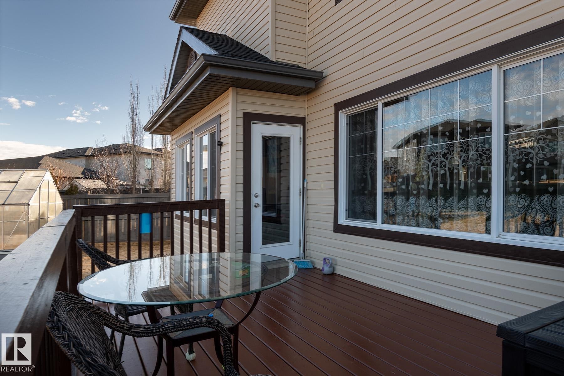 Expansive rear deck featuring wood-finish flooring, a full railing, and direct access to the interior via a glass-paneled door - 7426 Getty Way, Edmonton, AB - Outdoor With Deck Patio Veranda With Exterior