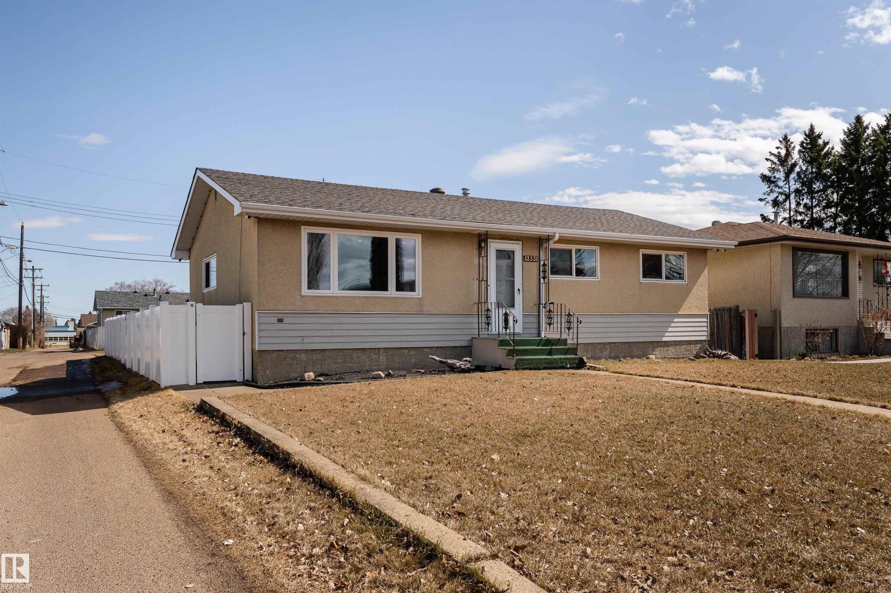 Single-story residence featuring a stucco exterior, white window trim, and a prominent front entrance with white railings - 13331 64 Street Nw, Edmonton, AB - Outdoor