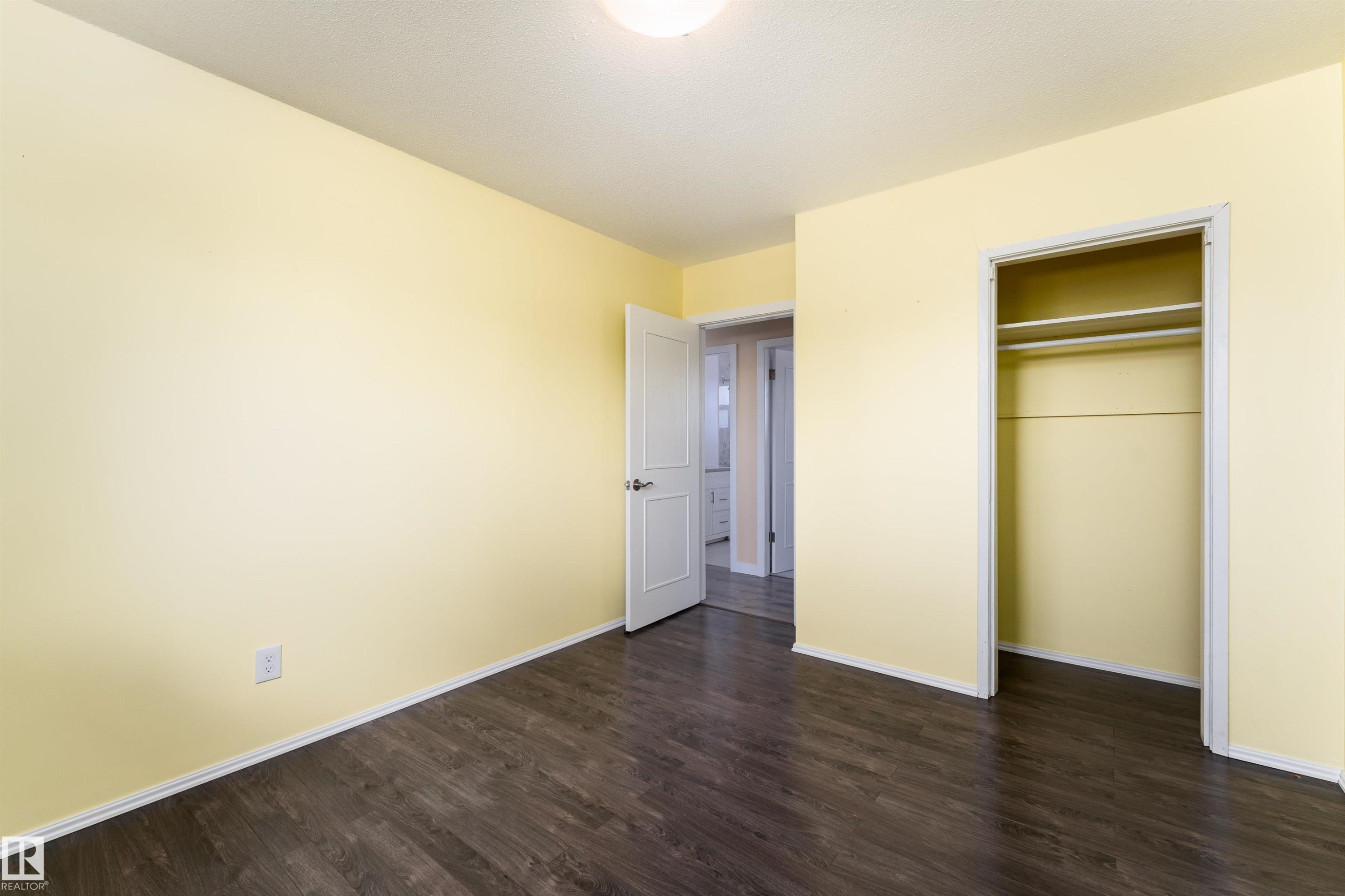 Room featuring wood-finish flooring, a bright wall color, a built-in closet with shelving, and white baseboards - 13331 64 Street Nw, Edmonton, AB - Indoor Photo Showing Other Room