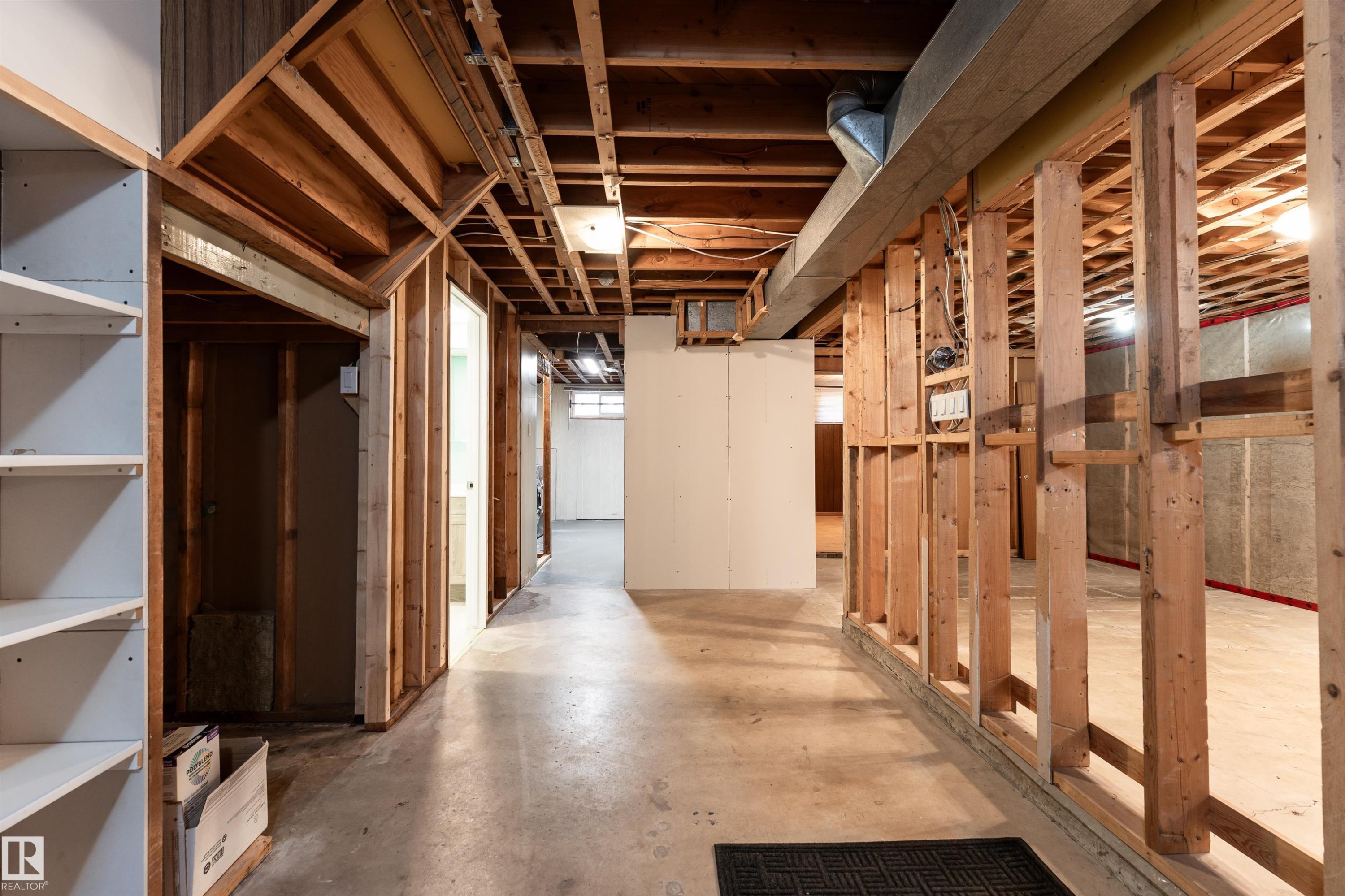 Unfinished basement featuring exposed wood framing, concrete flooring, visible ceiling joists, and white built-in shelving - 13331 64 Street Nw, Edmonton, AB - Indoor Photo Showing Basement