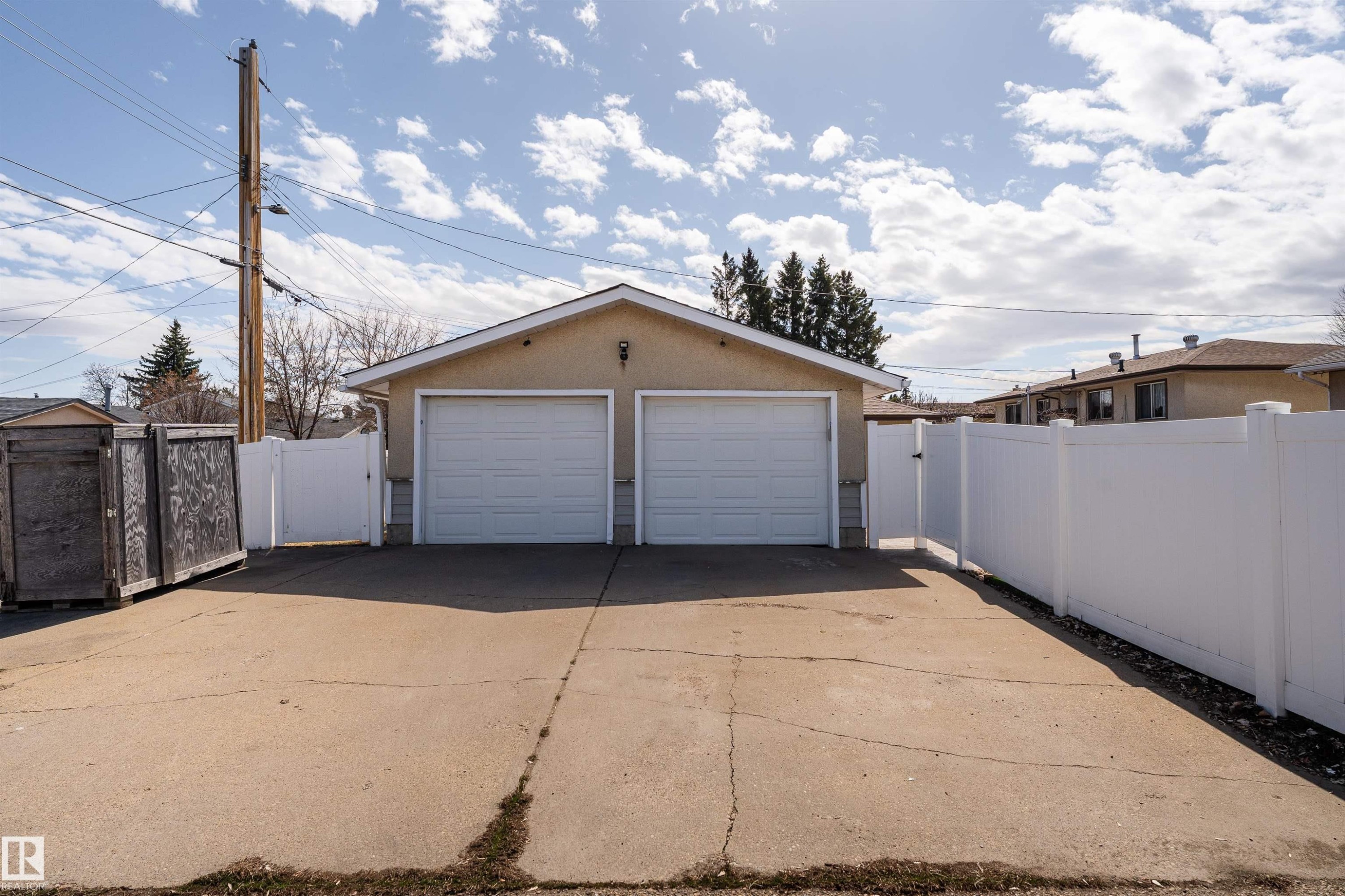 Detached two-car garage with white paneled doors, stucco exterior, and a gabled roofline - 13331 64 Street Nw, Edmonton, AB - Outdoor