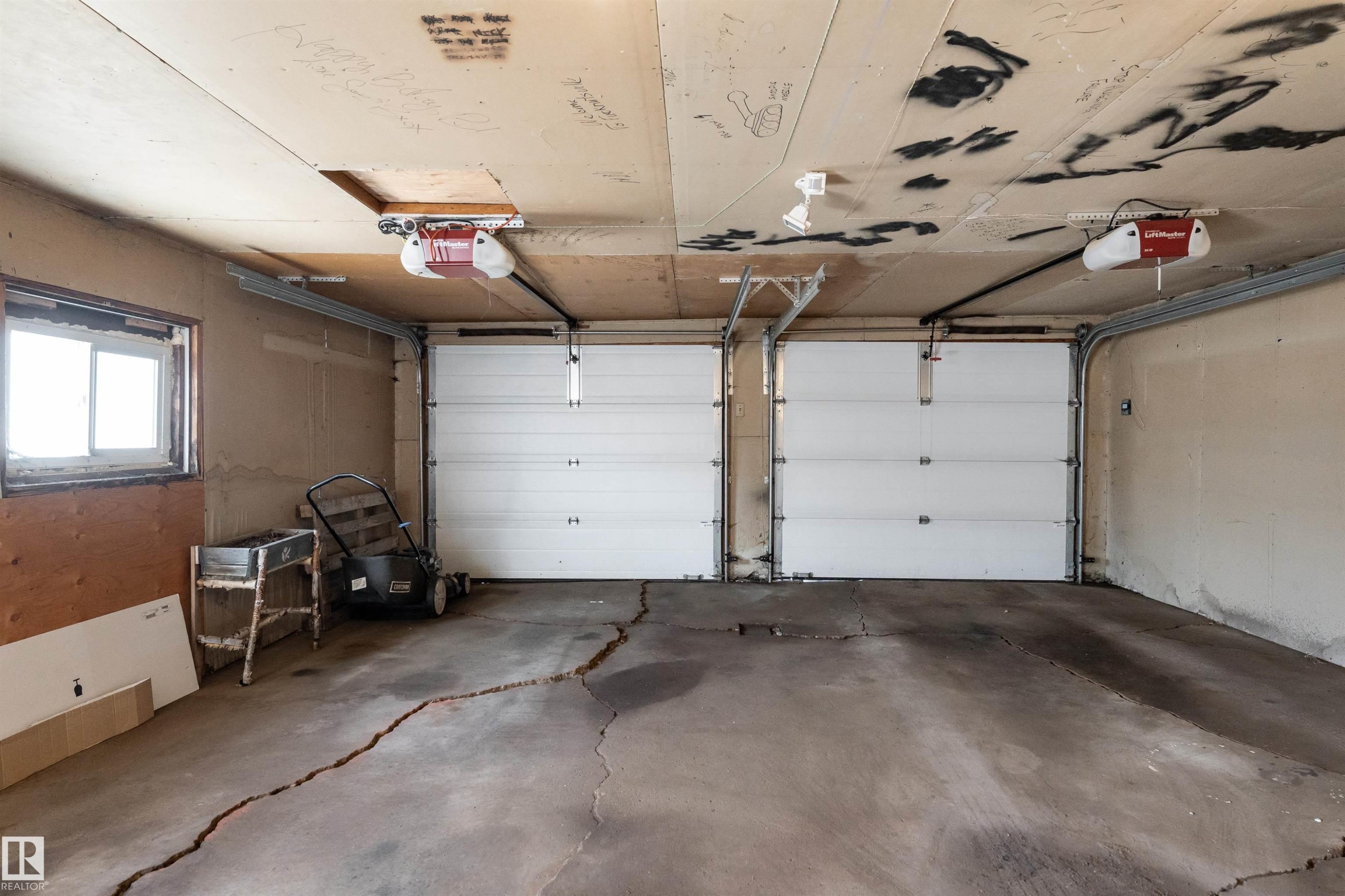 Two white sectional garage doors with overhead automatic openers - 13331 64 Street Nw, Edmonton, AB - Indoor Photo Showing Garage