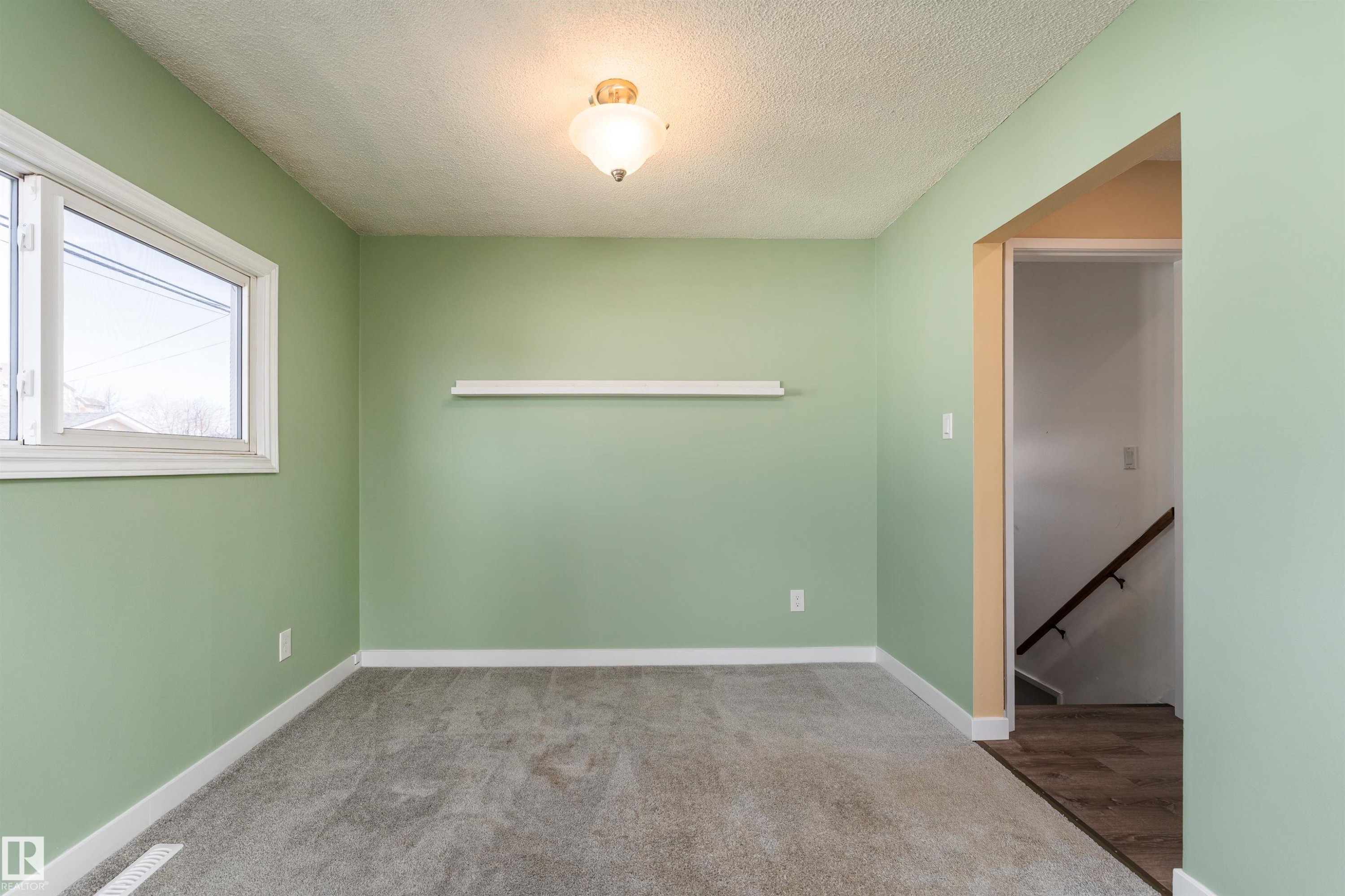 Carpeted room featuring a double-hung window with white trim, a ceiling-mounted light fixture, and a built-in wall shelf - 13331 64 Street Nw, Edmonton, AB - Indoor Photo Showing Other Room