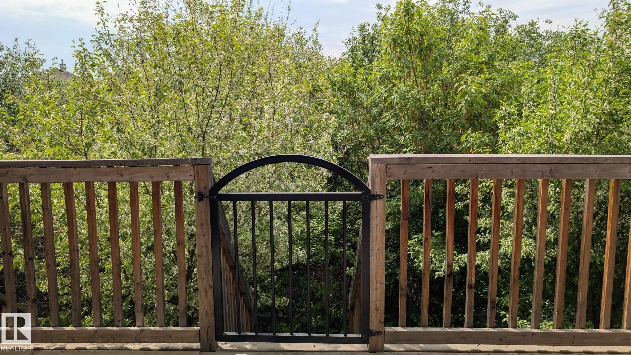 Wood deck featuring a black wrought iron gate with an arched top - #11 13215 153 Avenue, Edmonton, AB - Indoor Photo Showing Living Room With Fireplace