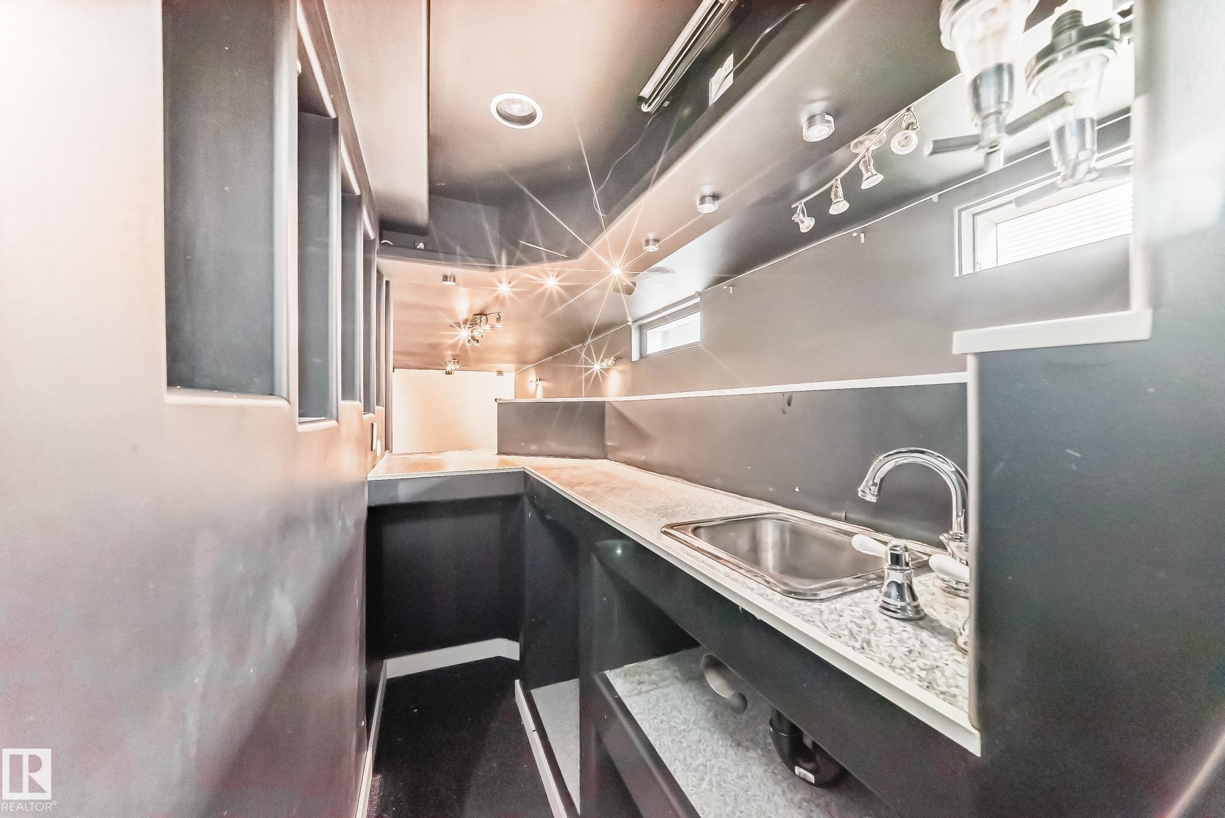 Compact wet bar area featuring a stainless steel sink, chrome faucet, and light-toned countertop - 5204 112 Avenue Nw, Edmonton, AB - Indoor Photo Showing Other Room