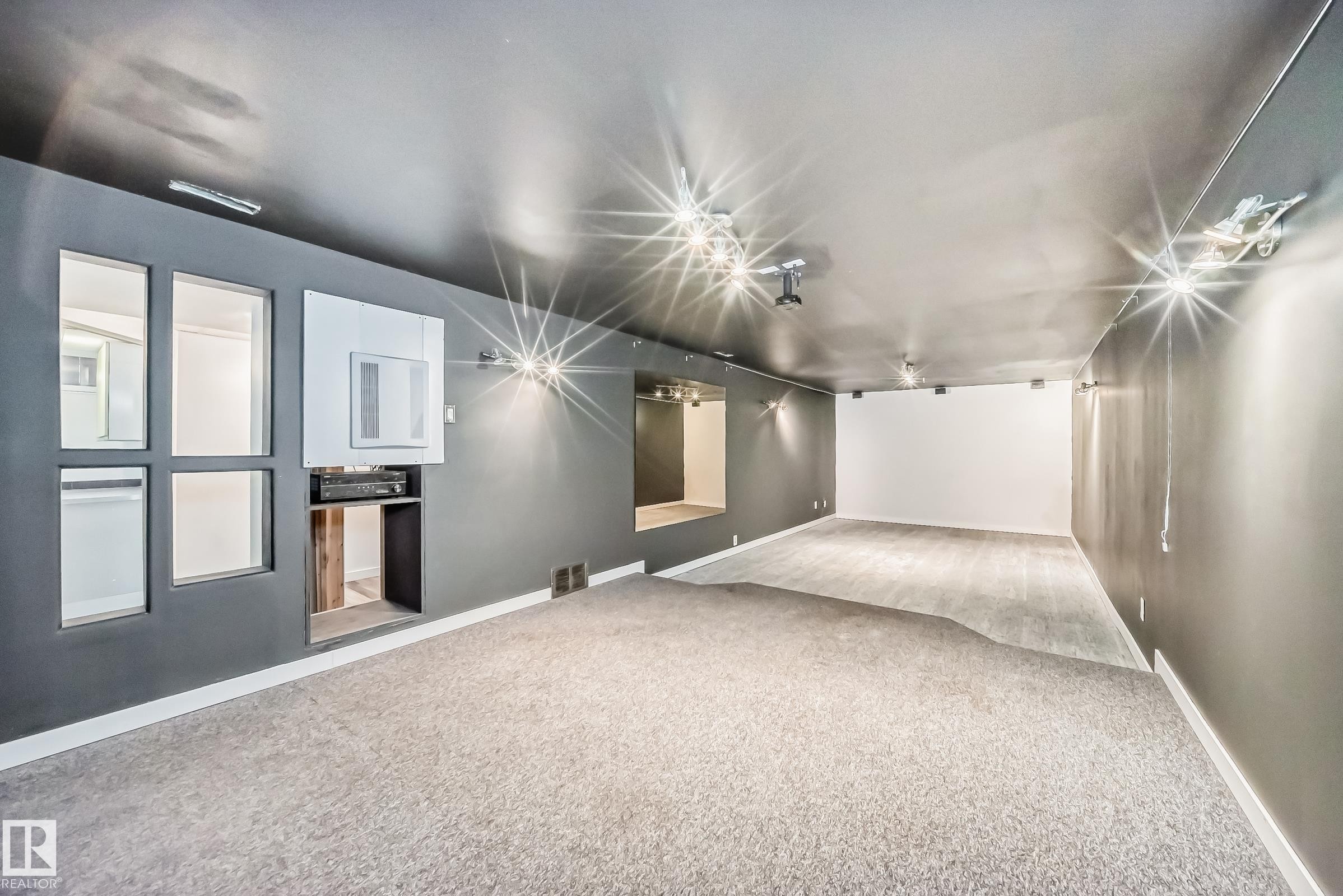 Spacious room featuring modern track lighting and a built-in media console - 5204 112 Avenue Nw, Edmonton, AB - Indoor Photo Showing Other Room