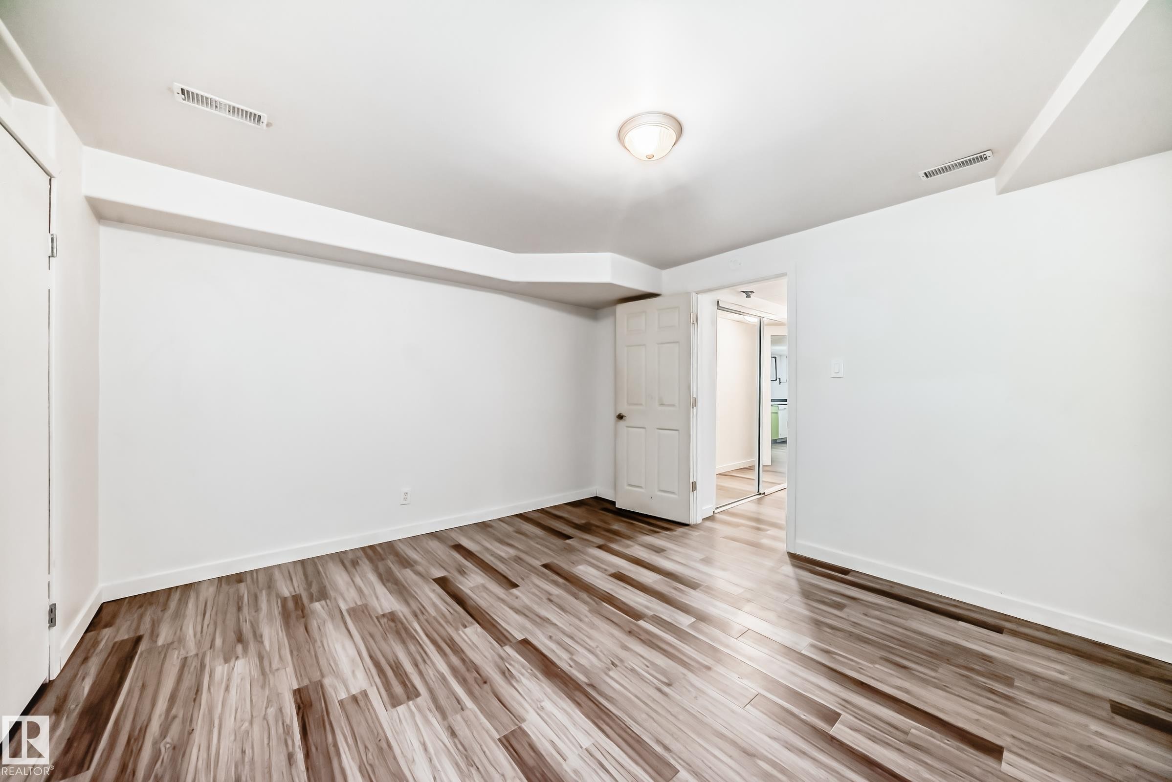 Spacious room featuring wood-finish flooring, white walls, and a white ceiling with recessed lighting - 5204 112 Avenue Nw, Edmonton, AB - Indoor Photo Showing Other Room