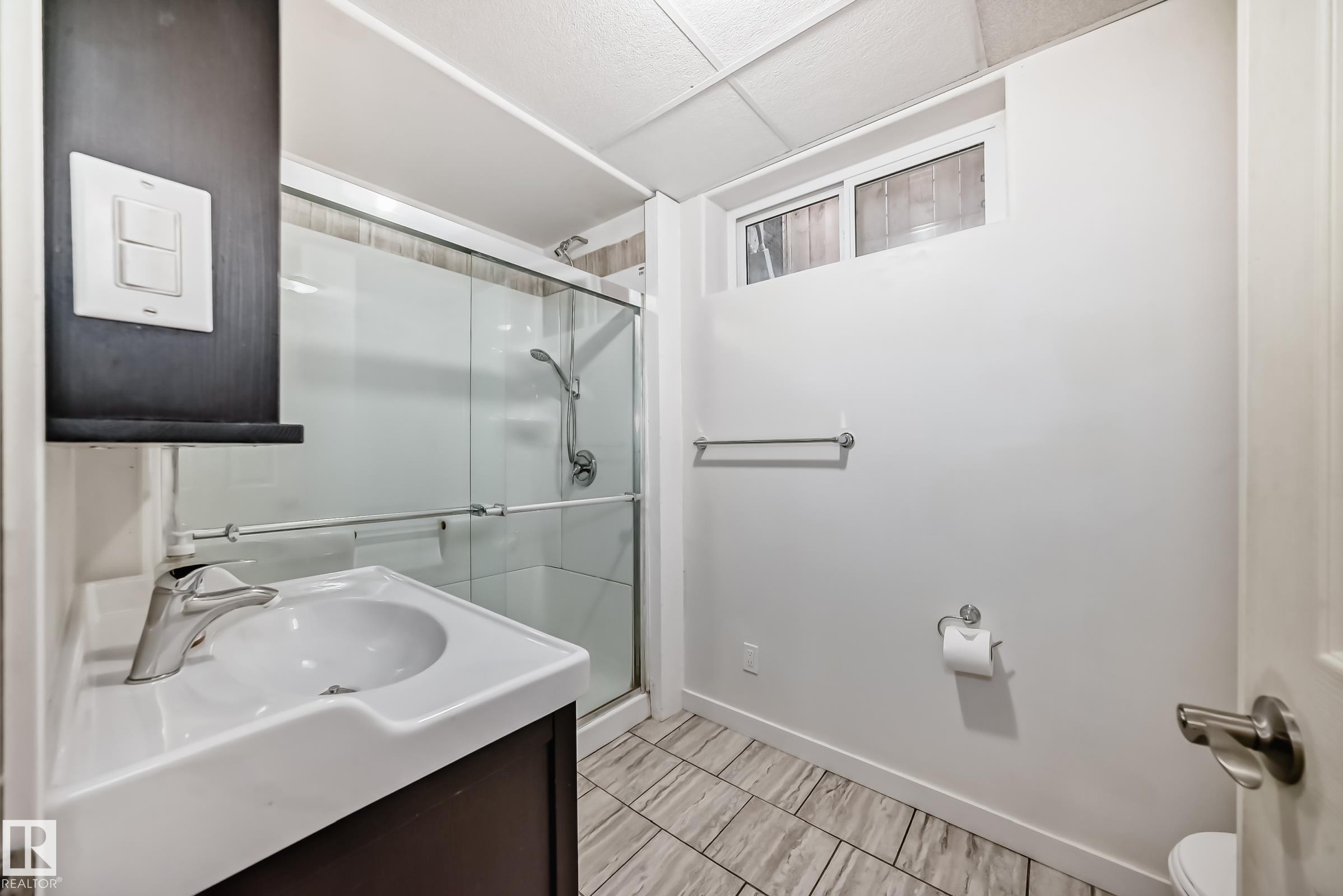 Bathroom featuring a vanity with an integrated sink, chrome faucet, and dark wood-finish cabinetry - 5204 112 Avenue Nw, Edmonton, AB - Indoor Photo Showing Bathroom