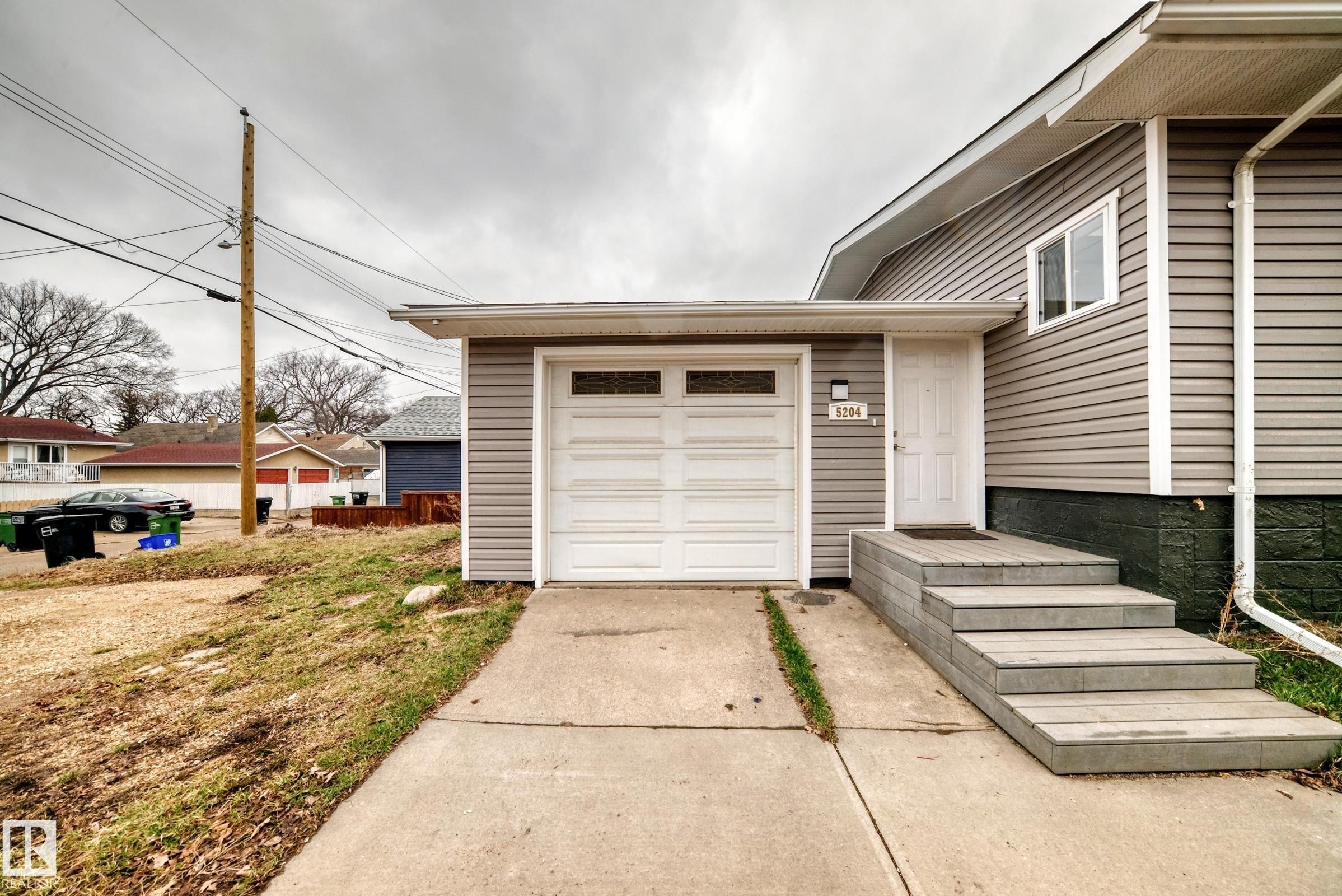 Siding exterior with a white garage door featuring transom windows - 5204 112 Avenue Nw, Edmonton, AB - Outdoor