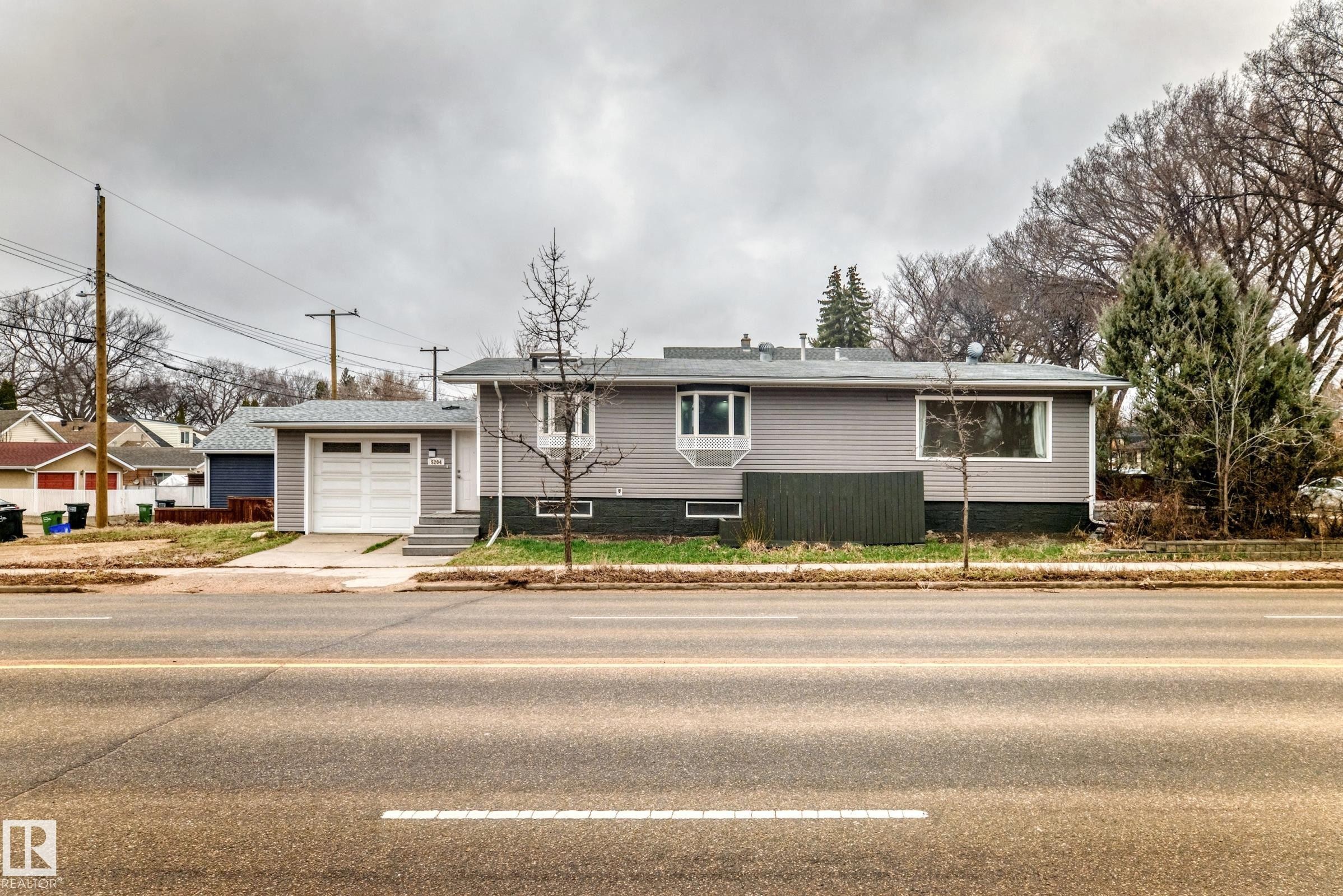 Grey siding exterior featuring white trim and a single-car garage with a white panel door - 5204 112 Avenue Nw, Edmonton, AB - Outdoor