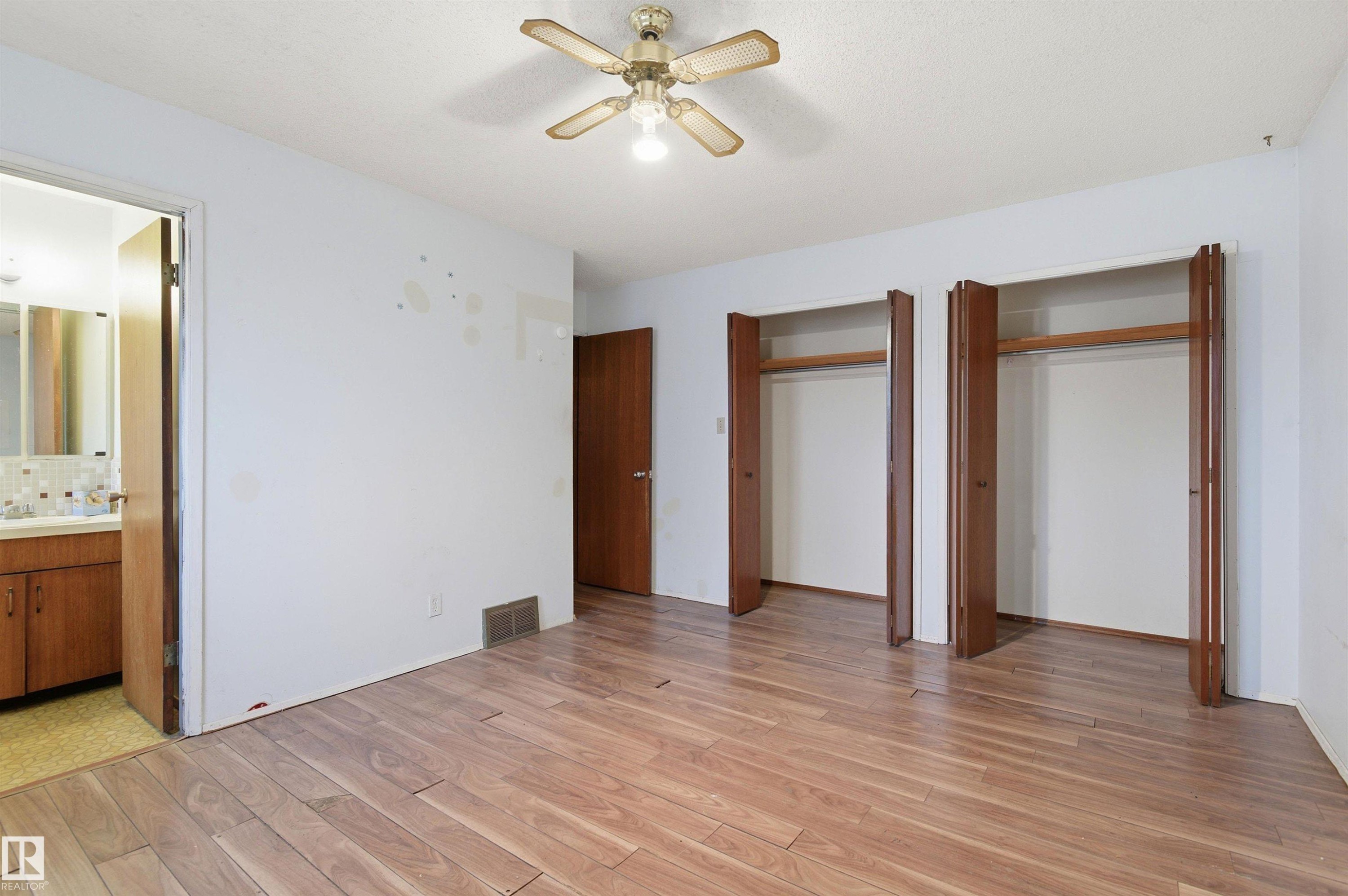 Spacious room featuring wood-finish flooring, a ceiling fan, and two wardrobes with bi-fold doors - 11211 77 Avenue, Edmonton, AB - Indoor Photo Showing Other Room