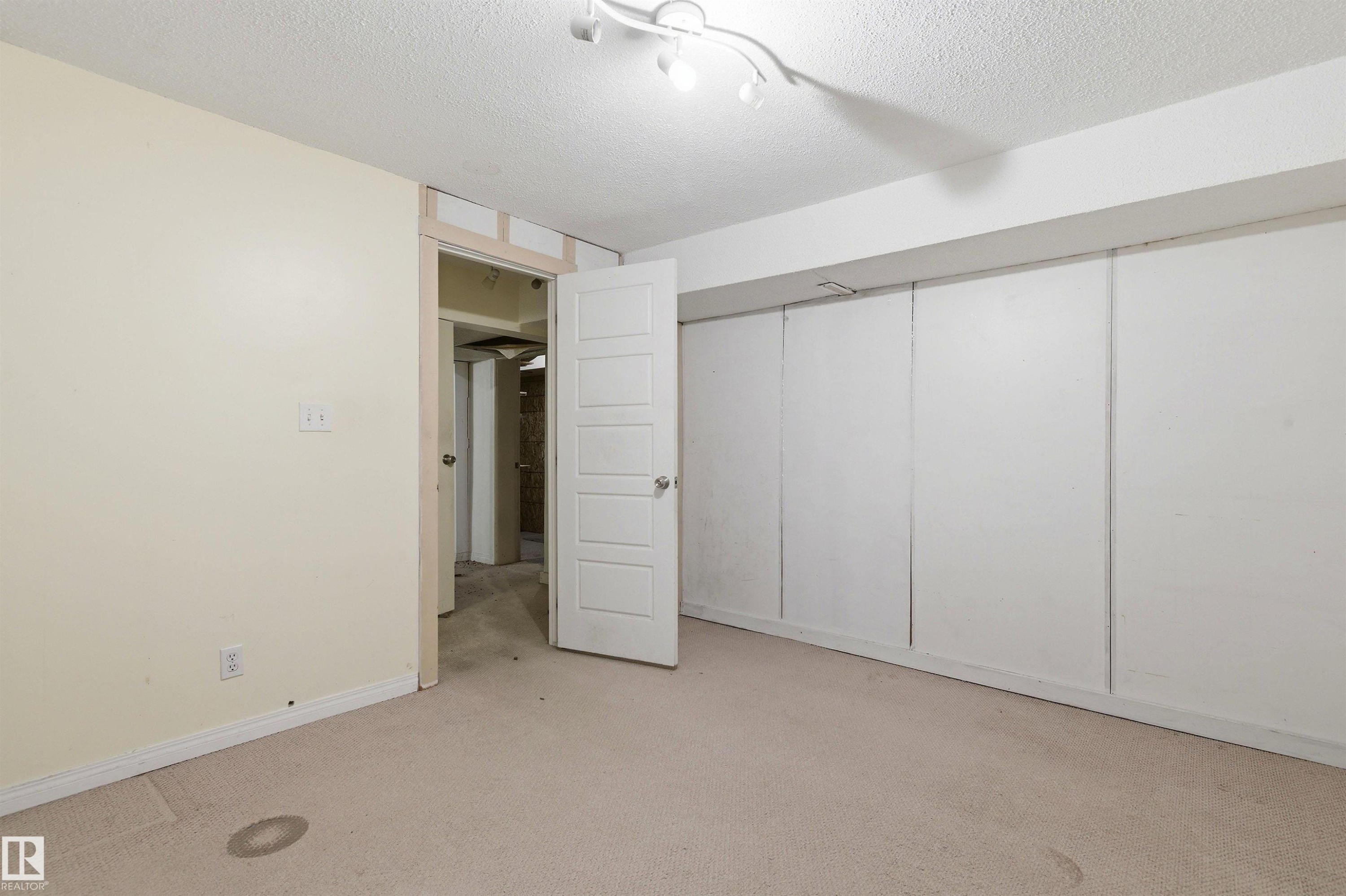 Carpeted room featuring light beige wall paint and a textured ceiling - 11211 77 Avenue, Edmonton, AB - Indoor Photo Showing Other Room