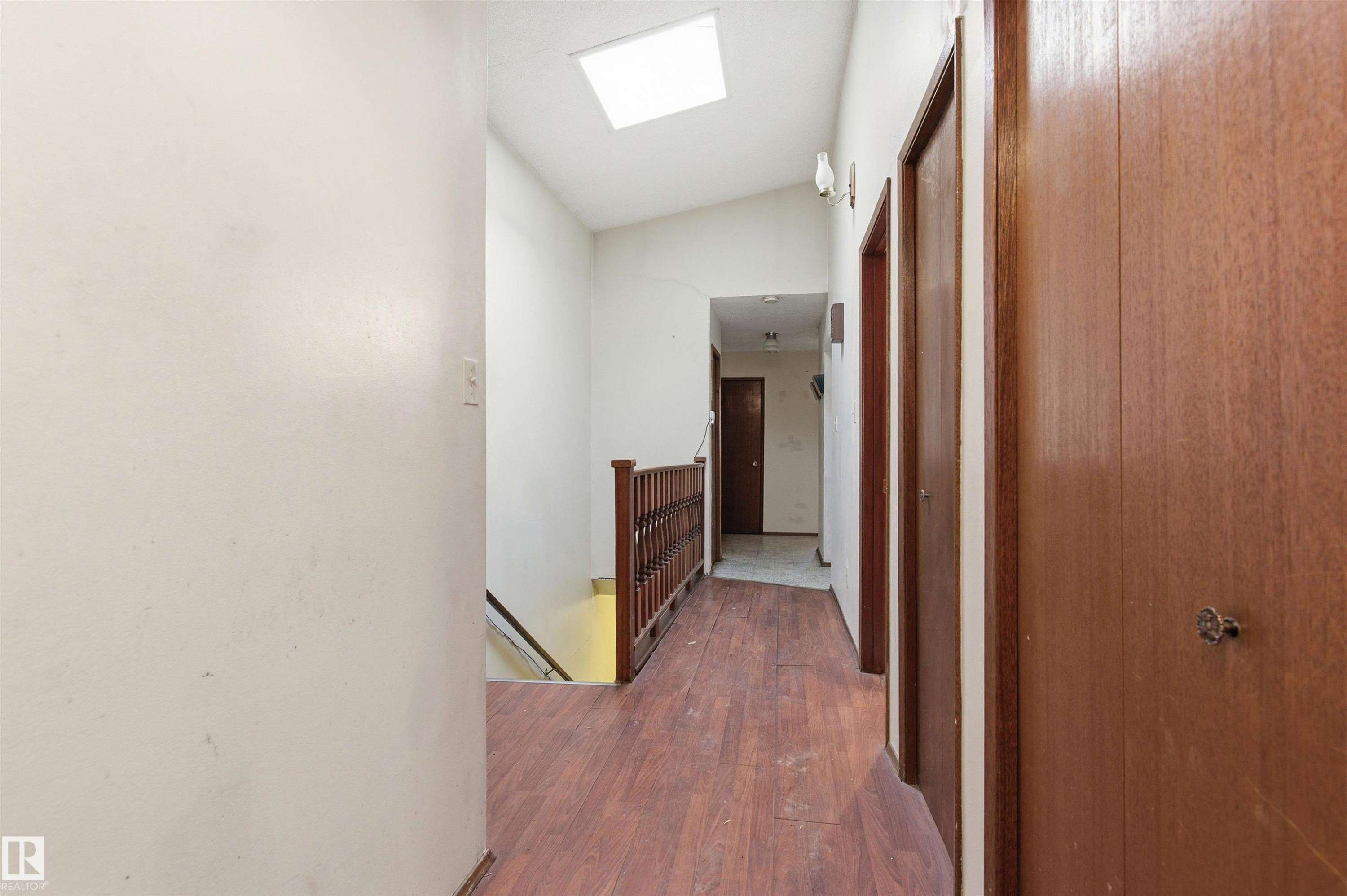 Hallway featuring wood-finish flooring, a skylight, and multiple panel doors - 11211 77 Avenue, Edmonton, AB - Indoor Photo Showing Other Room